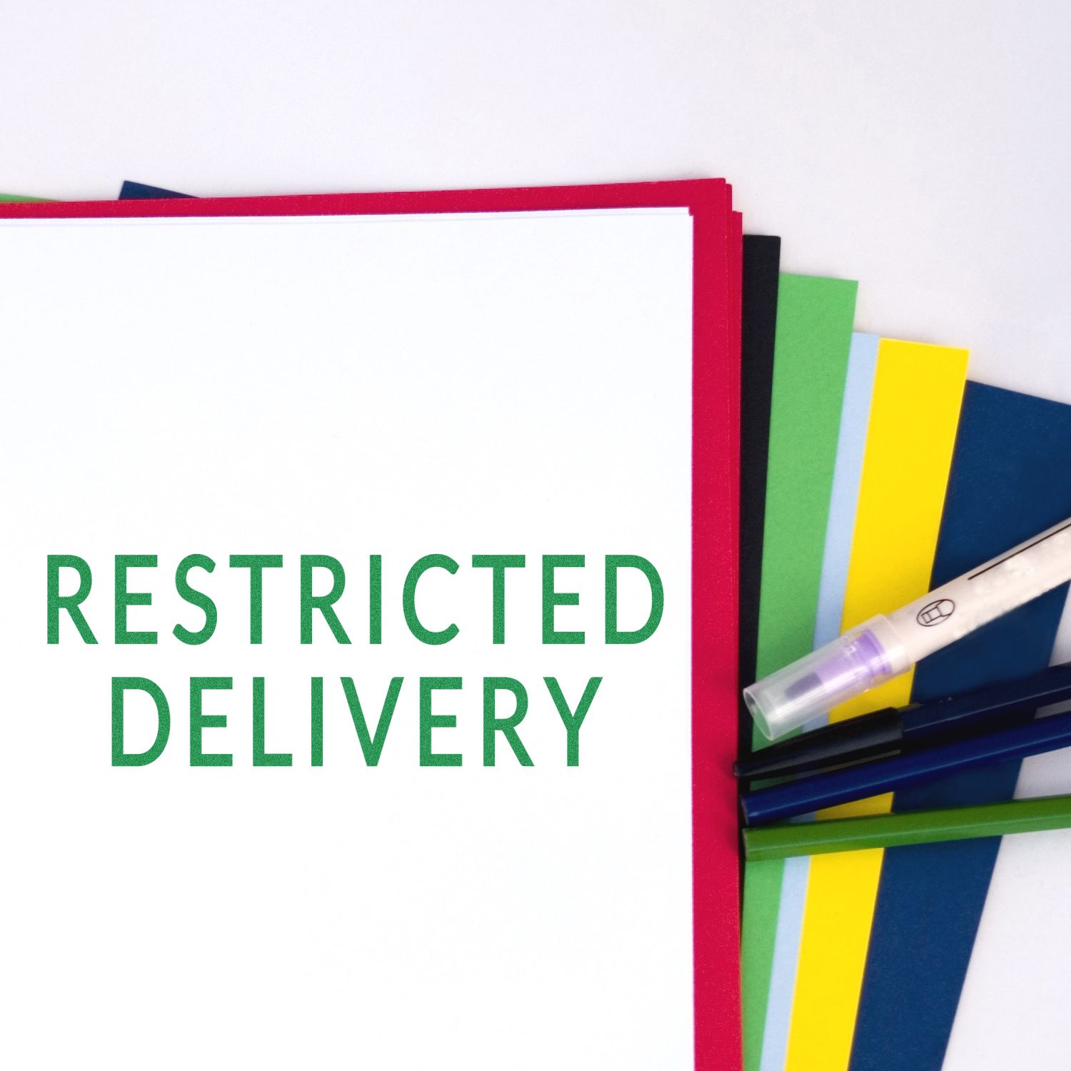 Self Inking Restricted Delivery Stamp in green ink on white paper, surrounded by colorful sheets and a pen on the side.