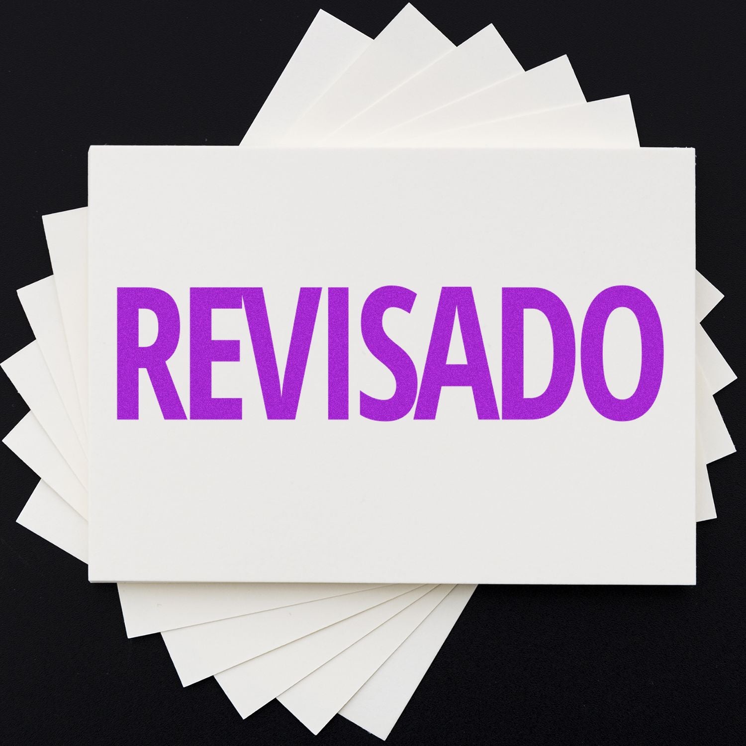 Self Inking Revisado Stamp in use, displaying the word REVISADO in bold purple letters on a white card, with more cards underneath.