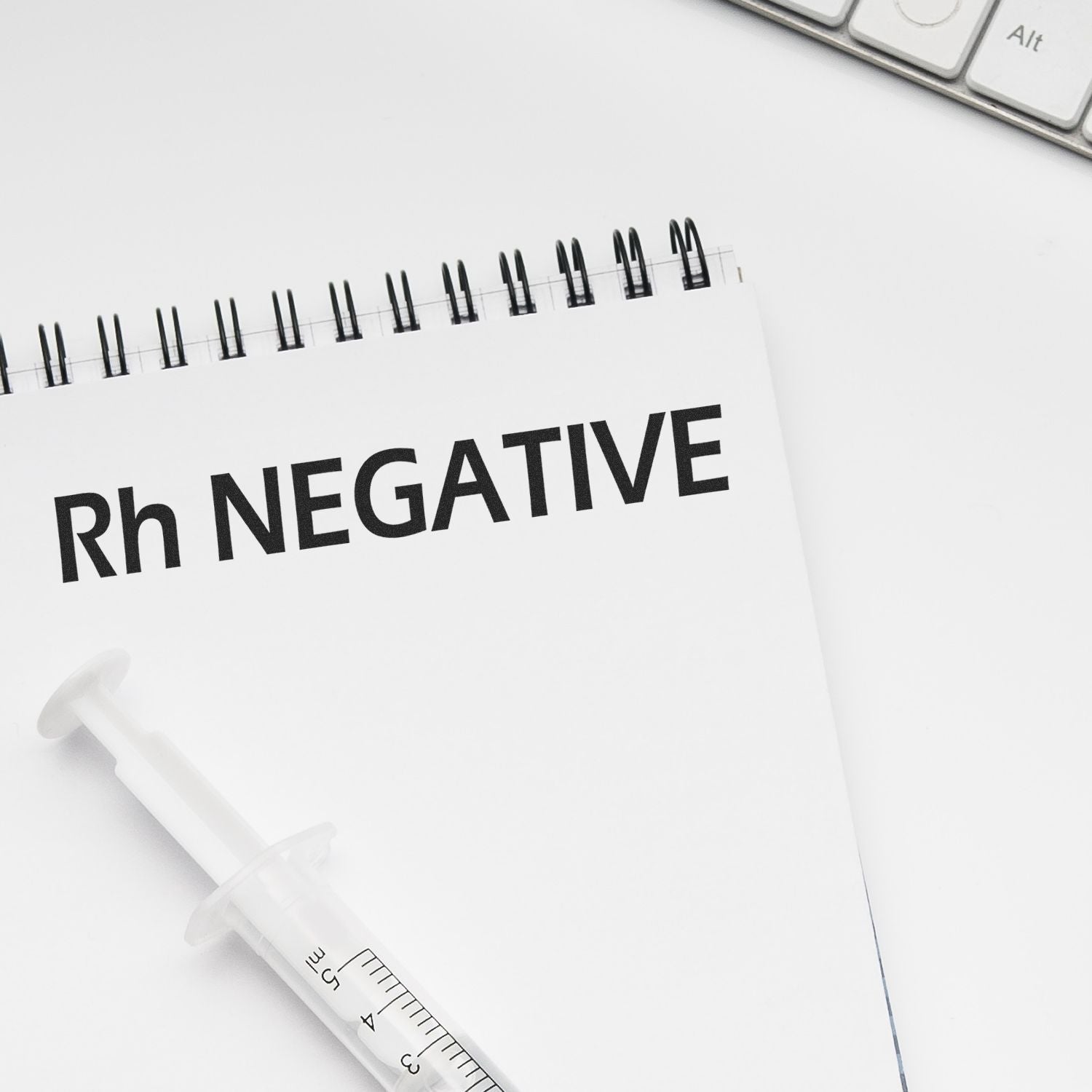 A Large Pre-Inked Rh Negative Stamp is used on a white notepad with Rh NEGATIVE text, next to a syringe and a keyboard.