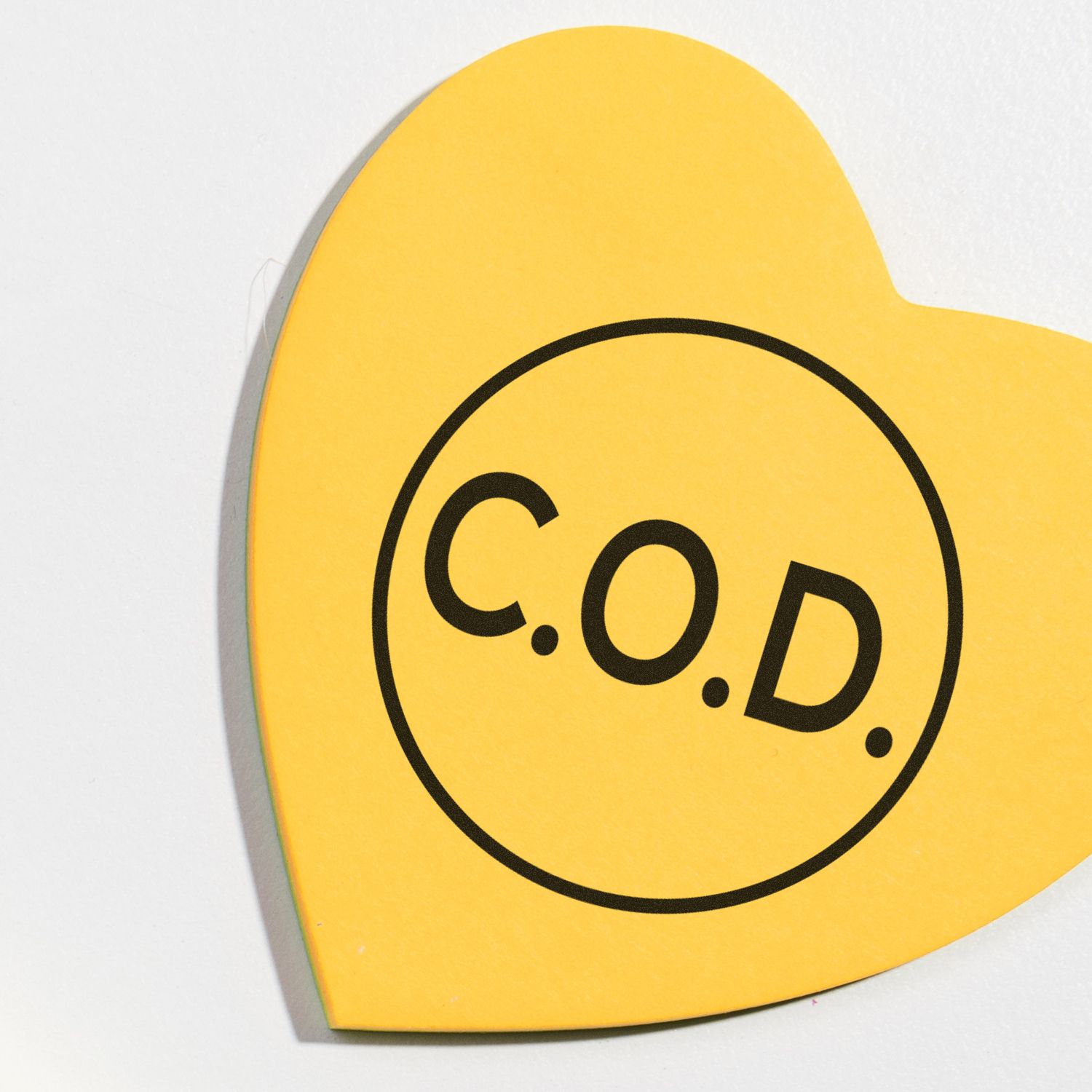 Yellow heart-shaped paper stamped with C.O.D. using the Self Inking Round COD Stamp.