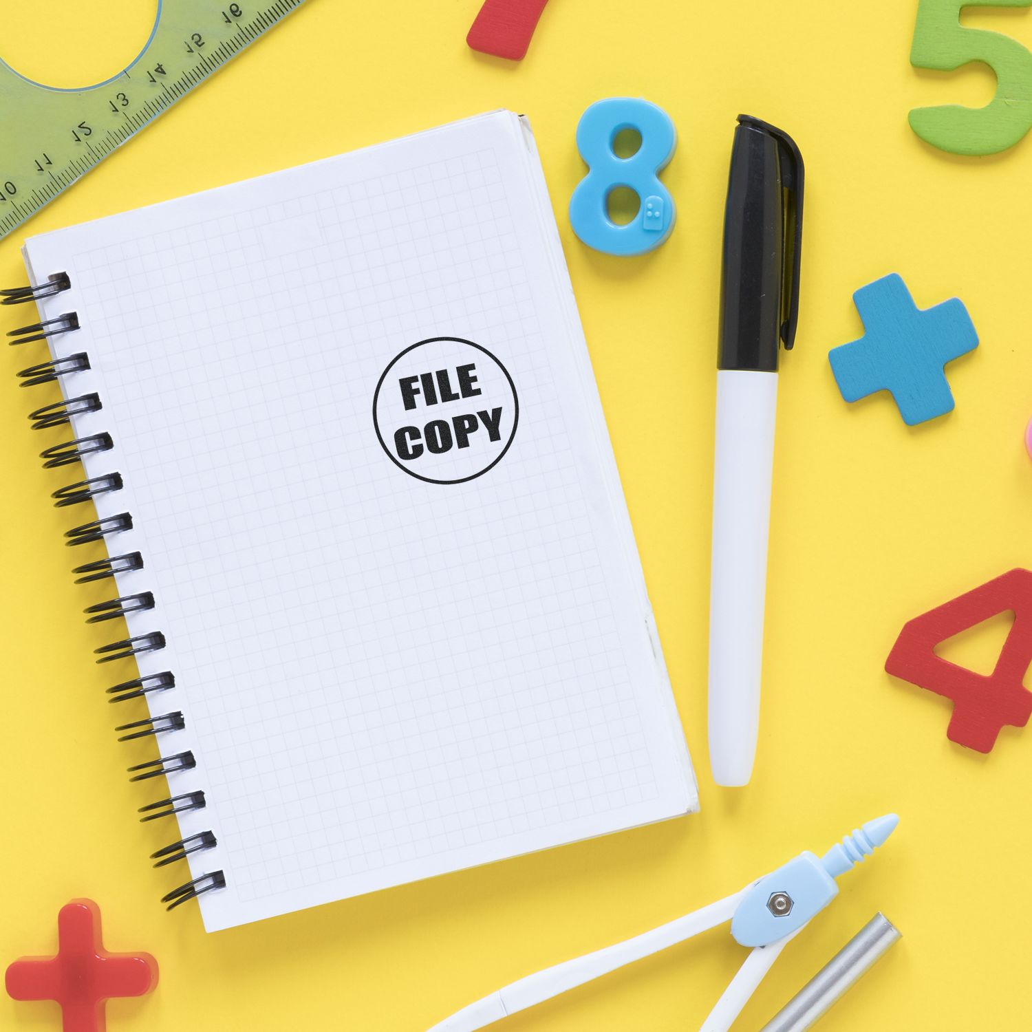 Notebook stamped with FILE COPY using Self Inking Round File Copy Stamp, surrounded by colorful numbers, pen, ruler, and compass on yellow background.