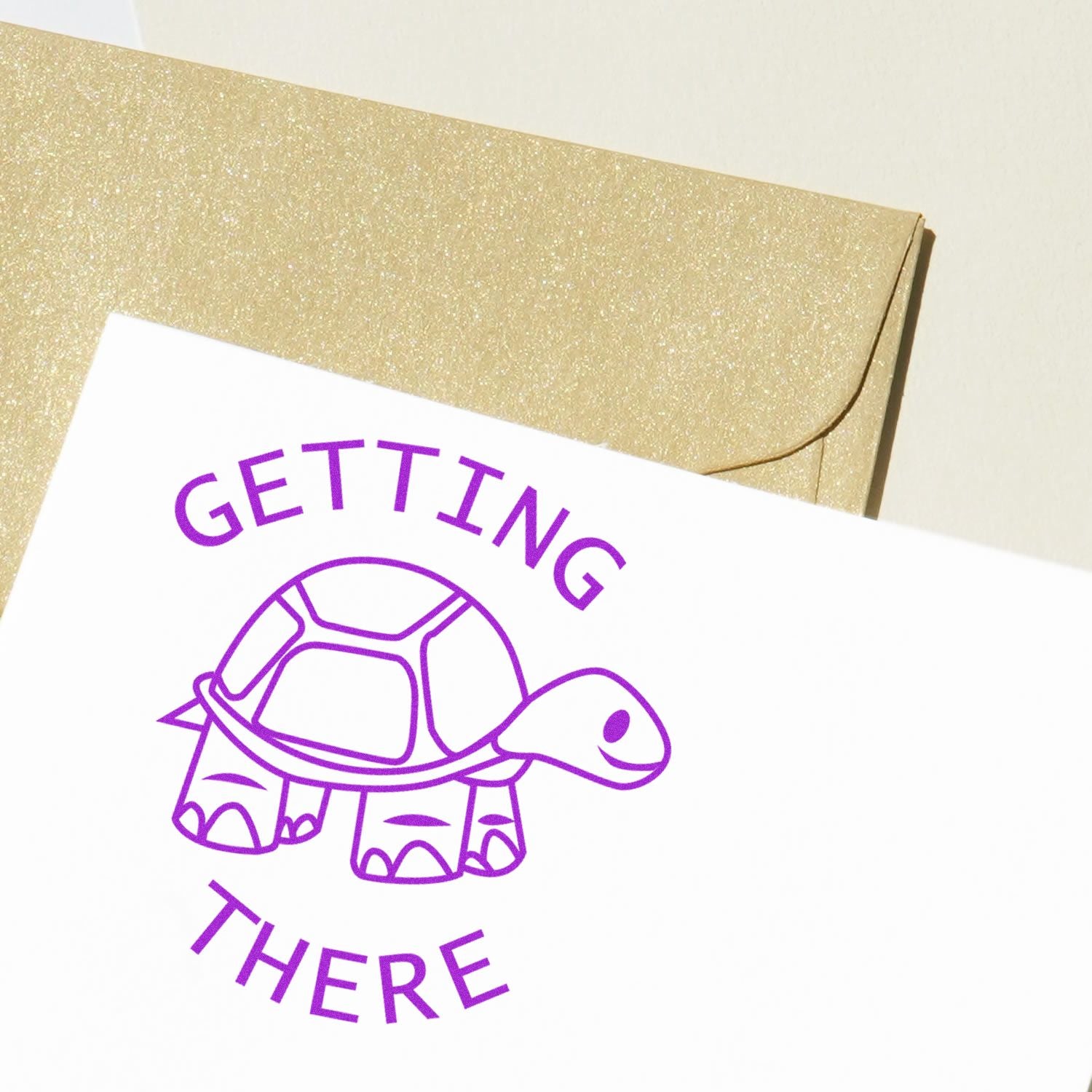 Round Getting There rubber stamp with a purple turtle design on white paper, placed next to a golden envelope.