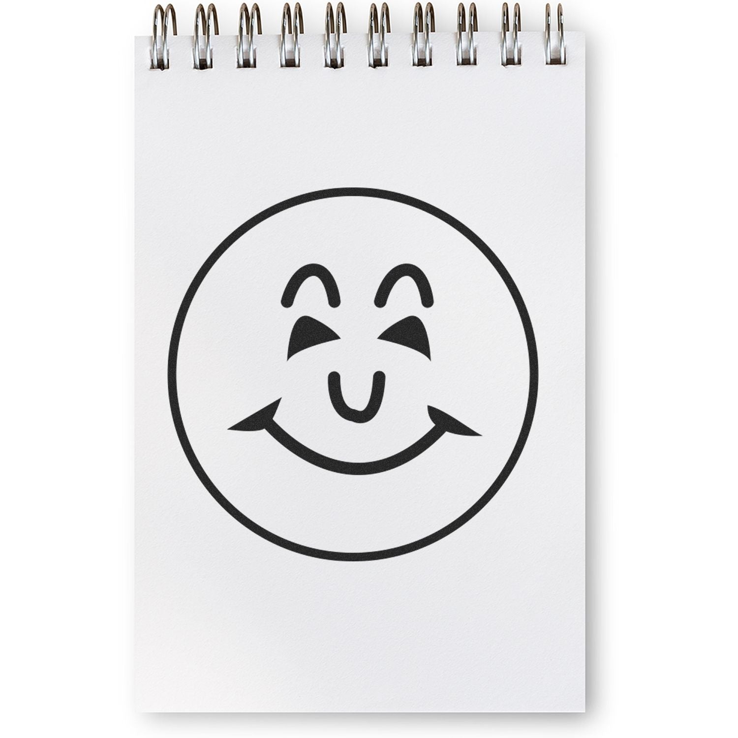 Self Inking Round Happy Face Stamp imprint on a white spiral notepad, showing a cheerful, smiling face with closed eyes.