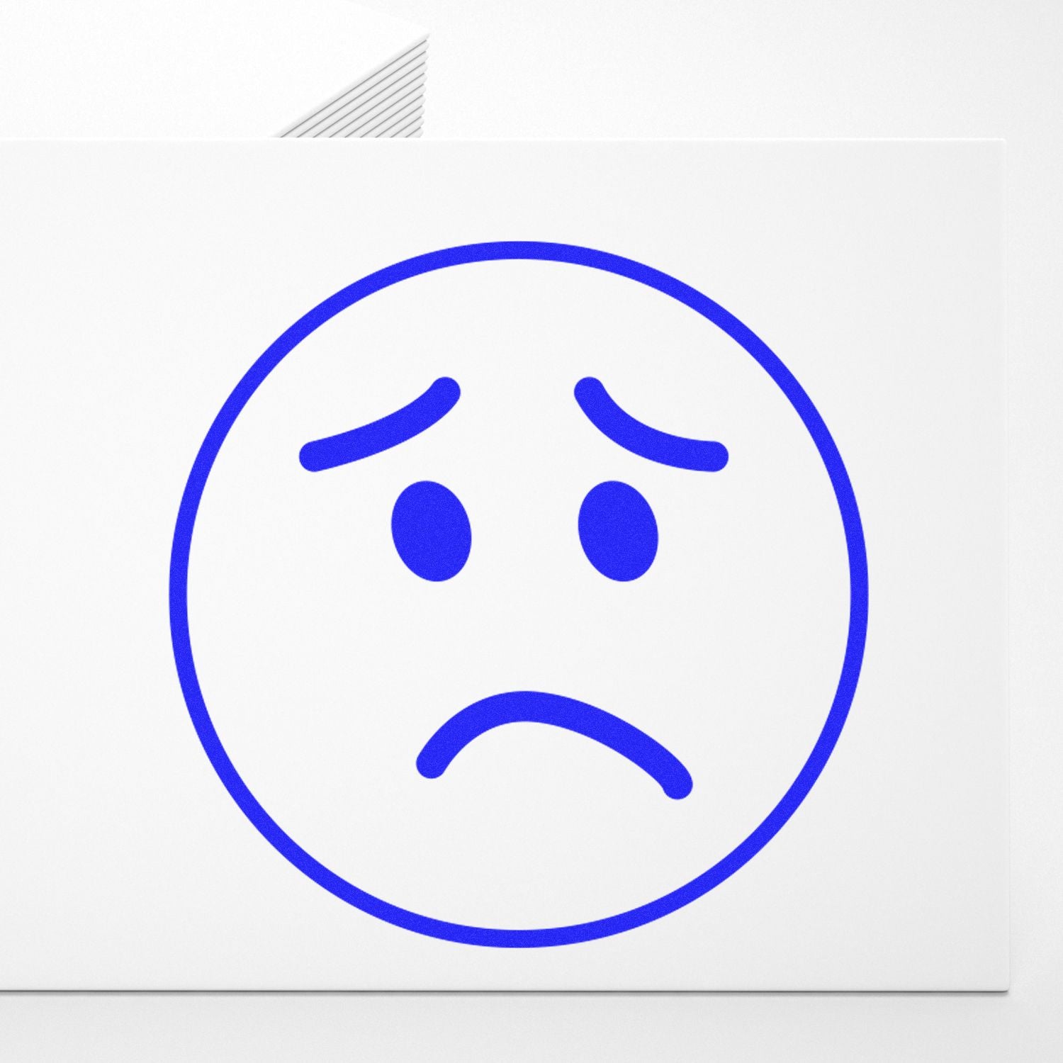 Round Sad Face Rubber Stamp in blue ink on white paper, showing a frowning face with downturned eyebrows and mouth.