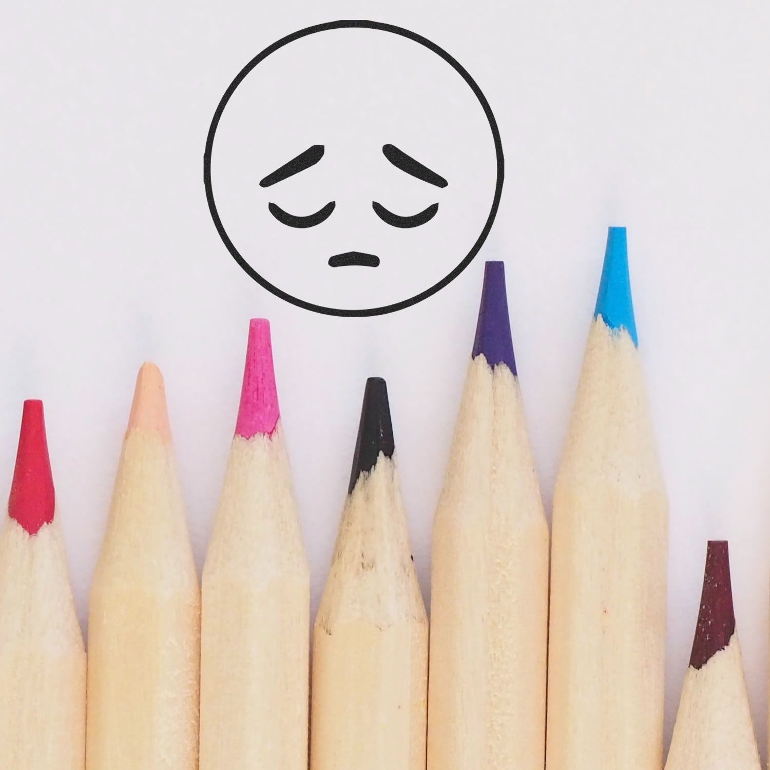 Colored pencils beneath a stamped sad face using the Self Inking Round Sad Smiley Stamp.