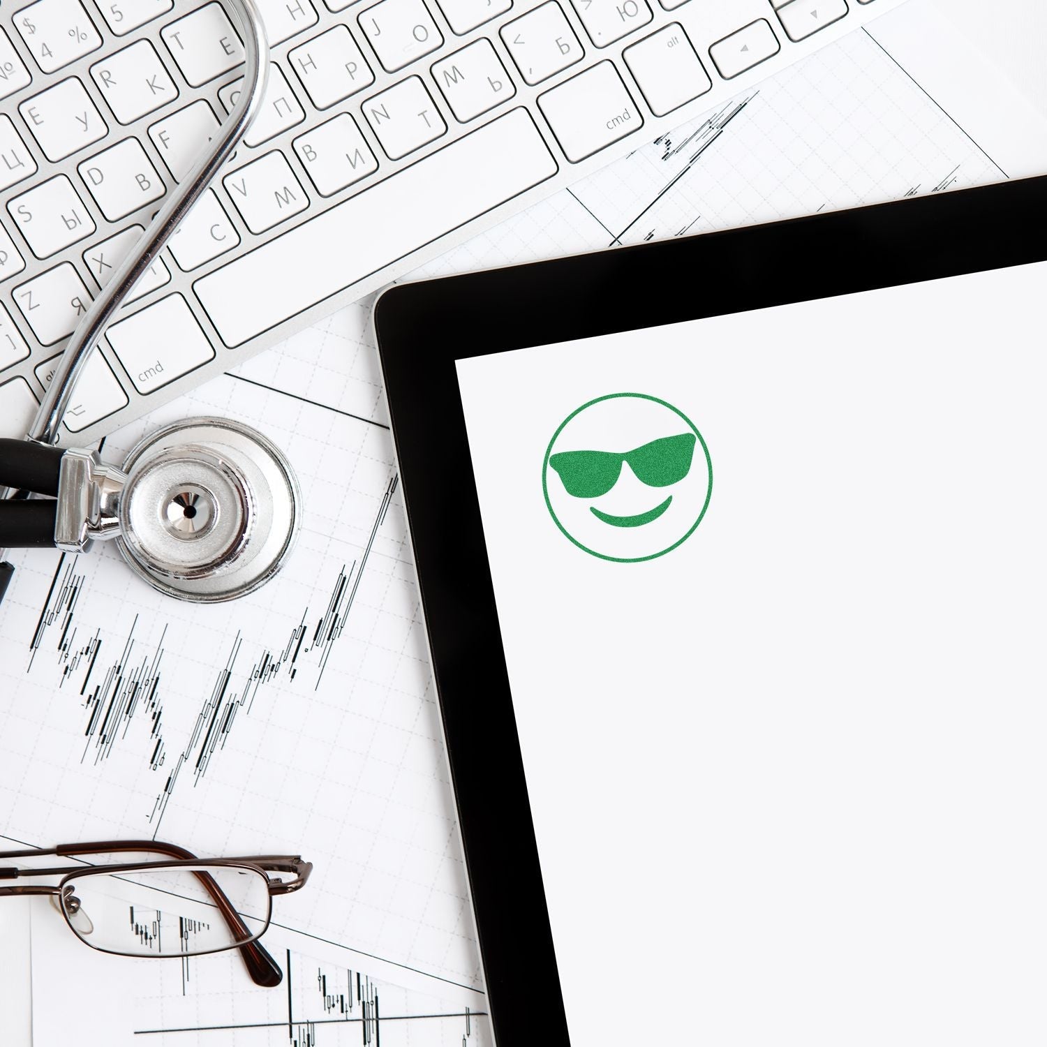 Self Inking Round Smiley with Sunglasses Stamp on paper near a keyboard, stethoscope, glasses, and tablet.