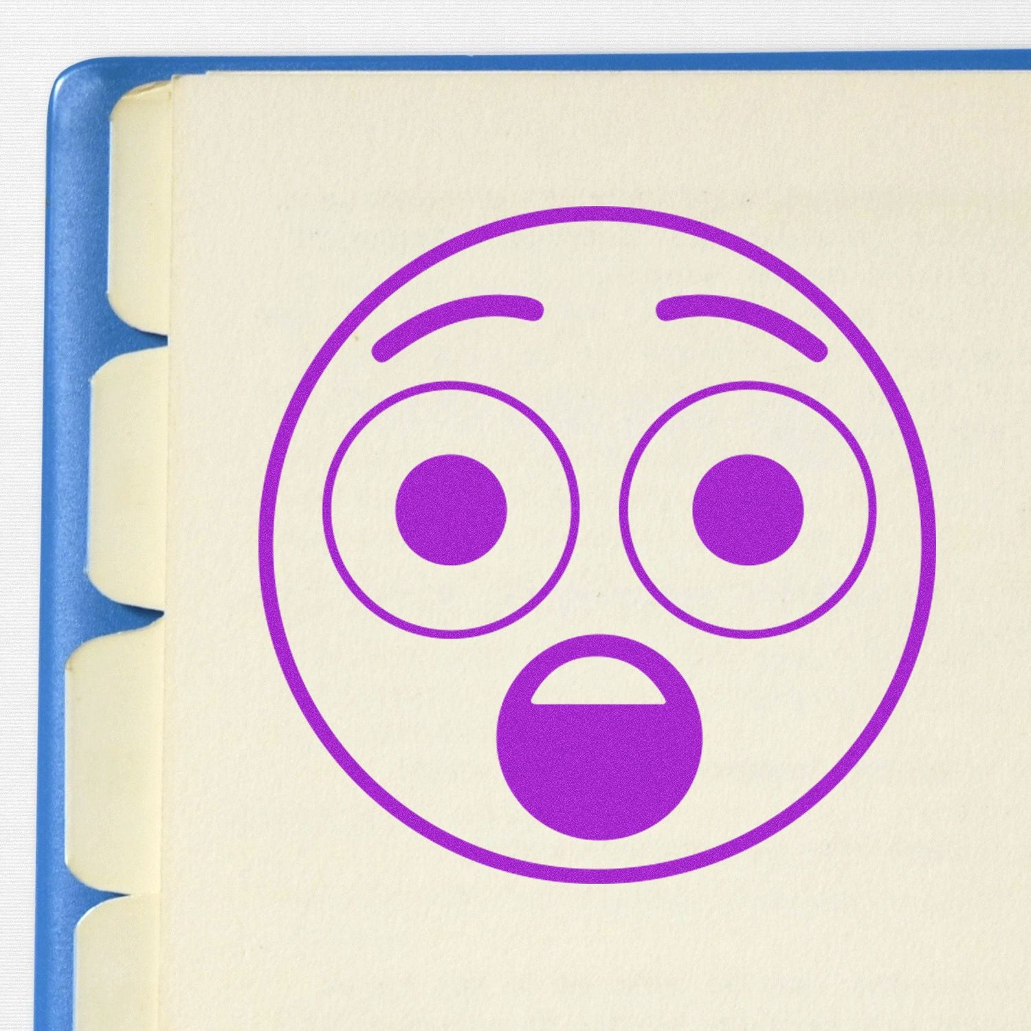 Round Surprised Smiley Rubber Stamp in purple ink on a notebook page with a blue binder edge visible.