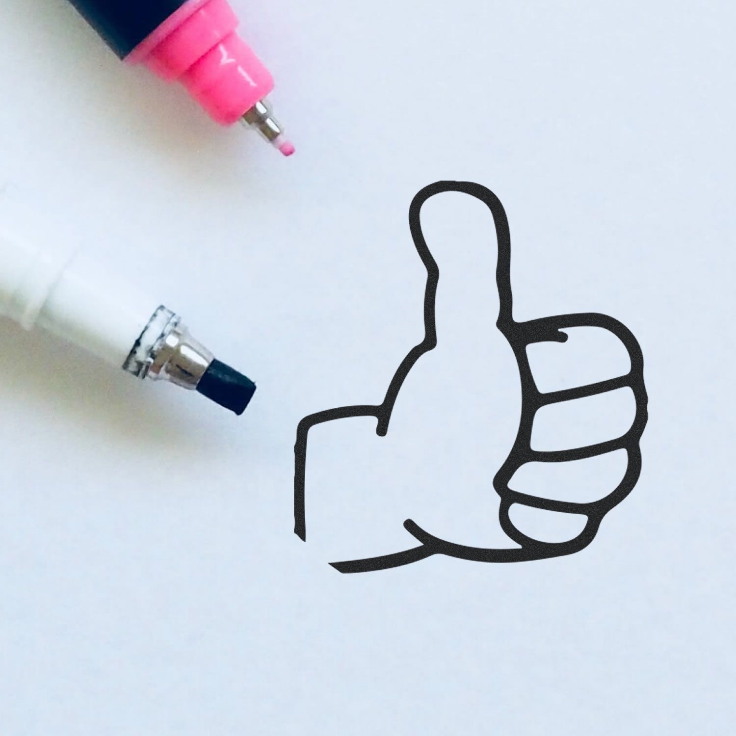 Round Thumbs Up Rubber Stamp impression on white paper with pink and black markers nearby.