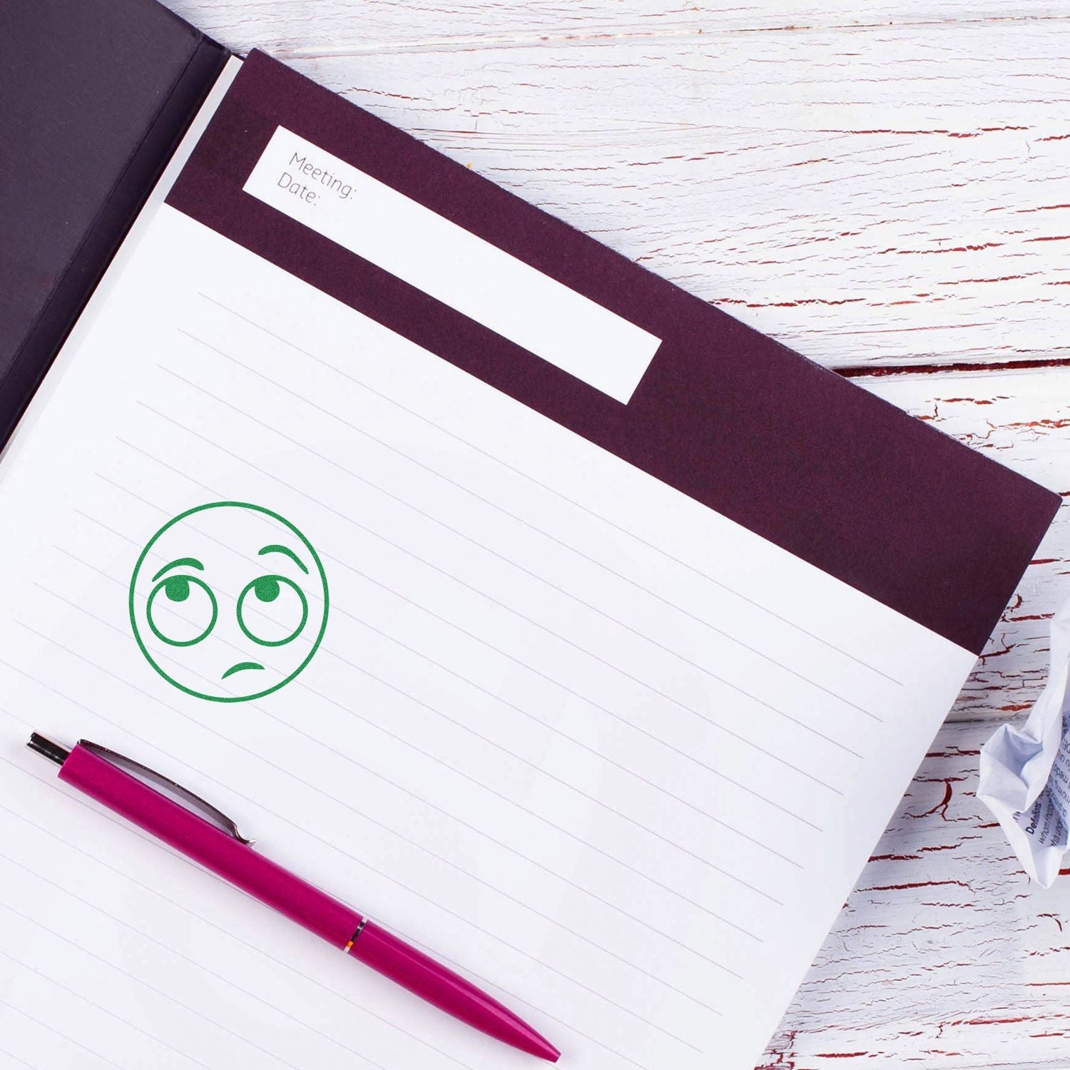 Self Inking Round Whatever Smiley Stamp in use on a notebook with a pink pen beside it, displaying a green indifferent smiley face.