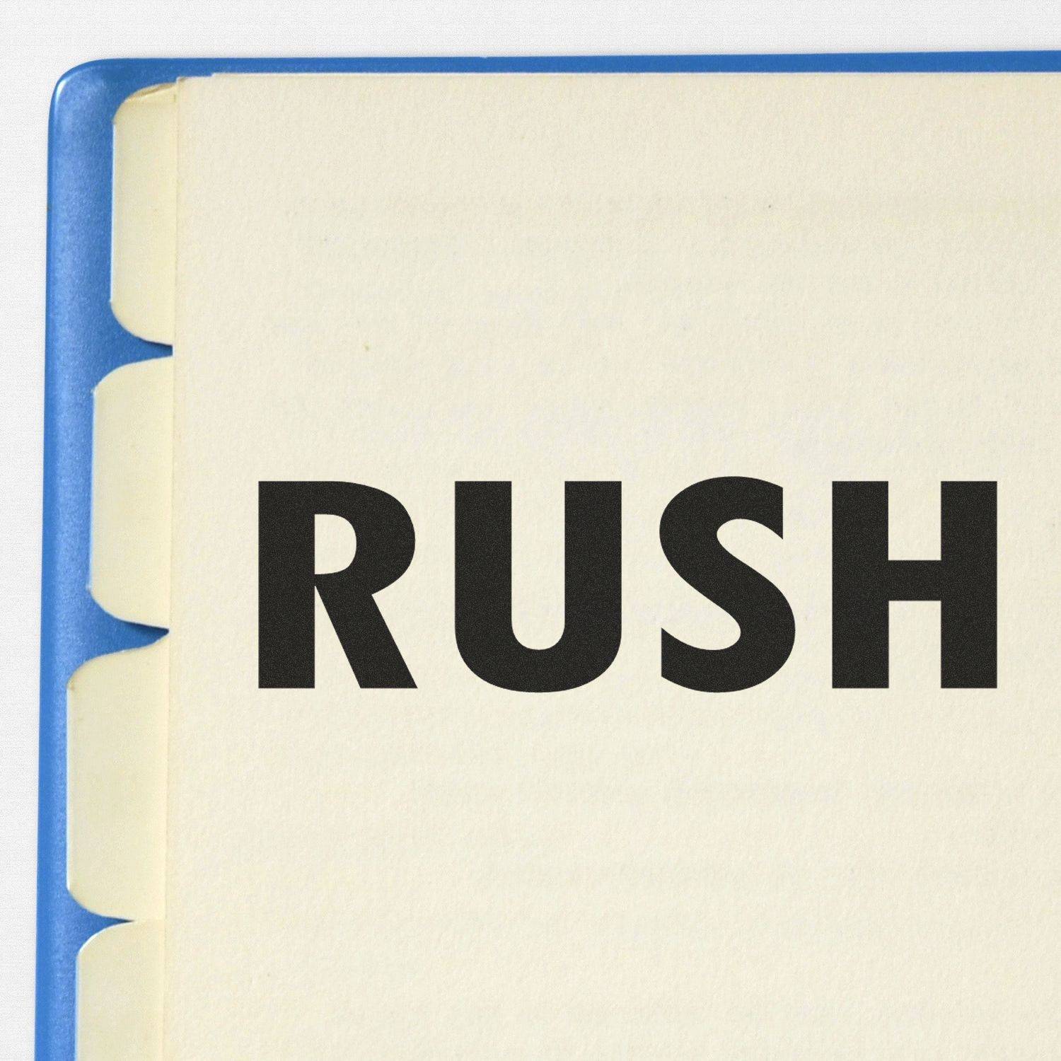 Large Rush Rubber Stamp used on a document, creating a bold "RUSH" mark in black ink on a white page with blue binder tabs visible.