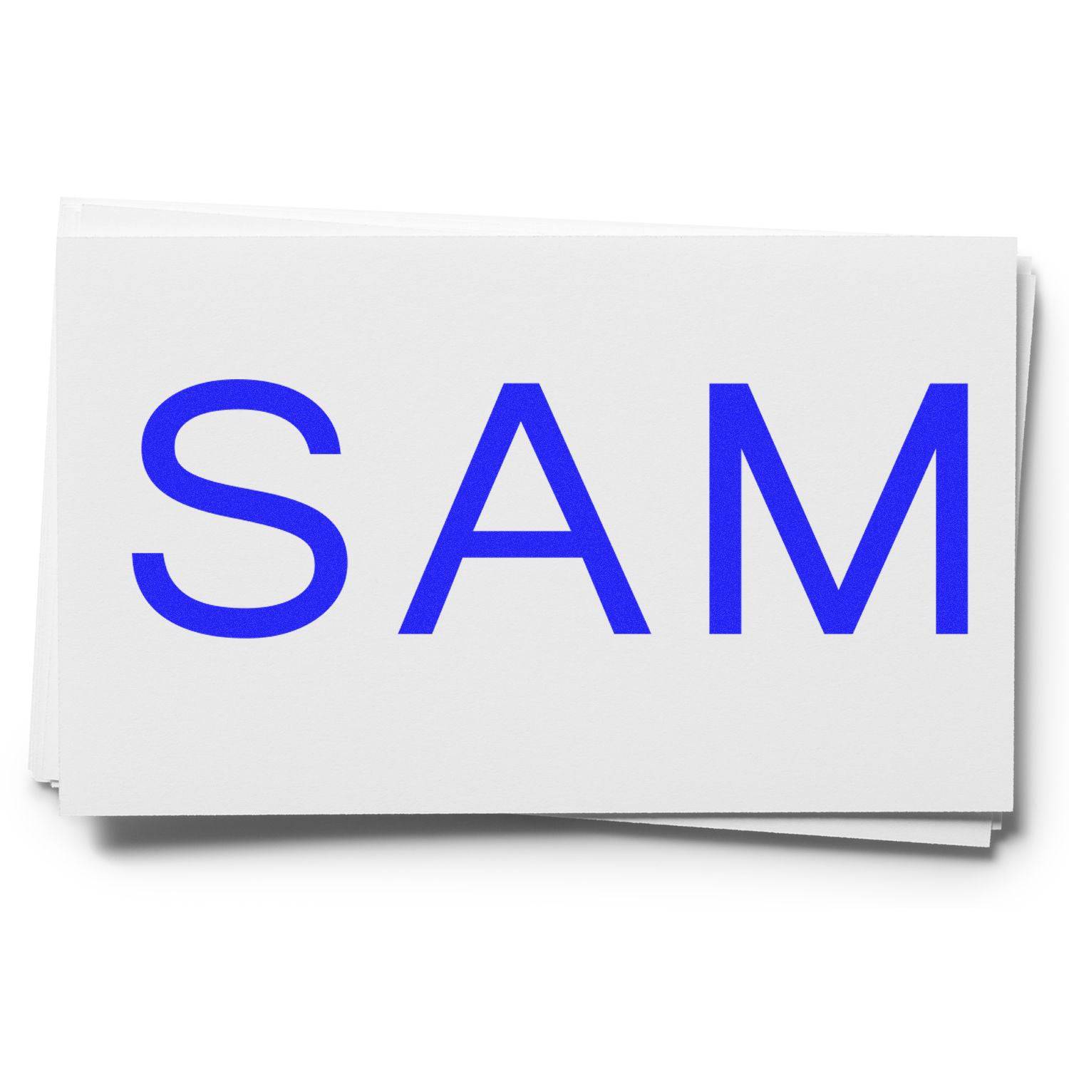 Large SAM Rubber Stamp in use, creating a bold blue "SAM" imprint on white paper.