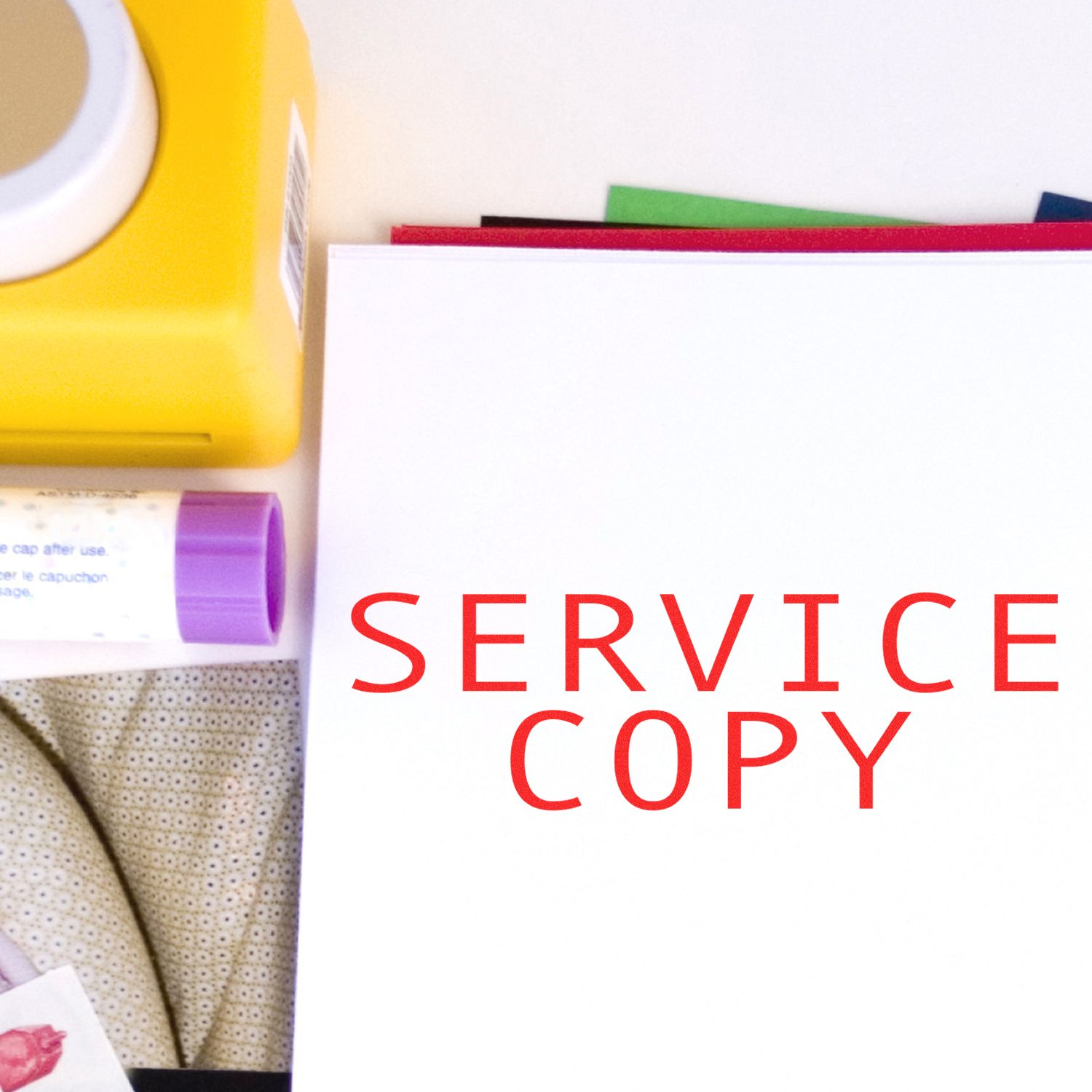 Large Service Copy rubber stamp on white paper, surrounded by office supplies including a yellow stapler and a glue stick.