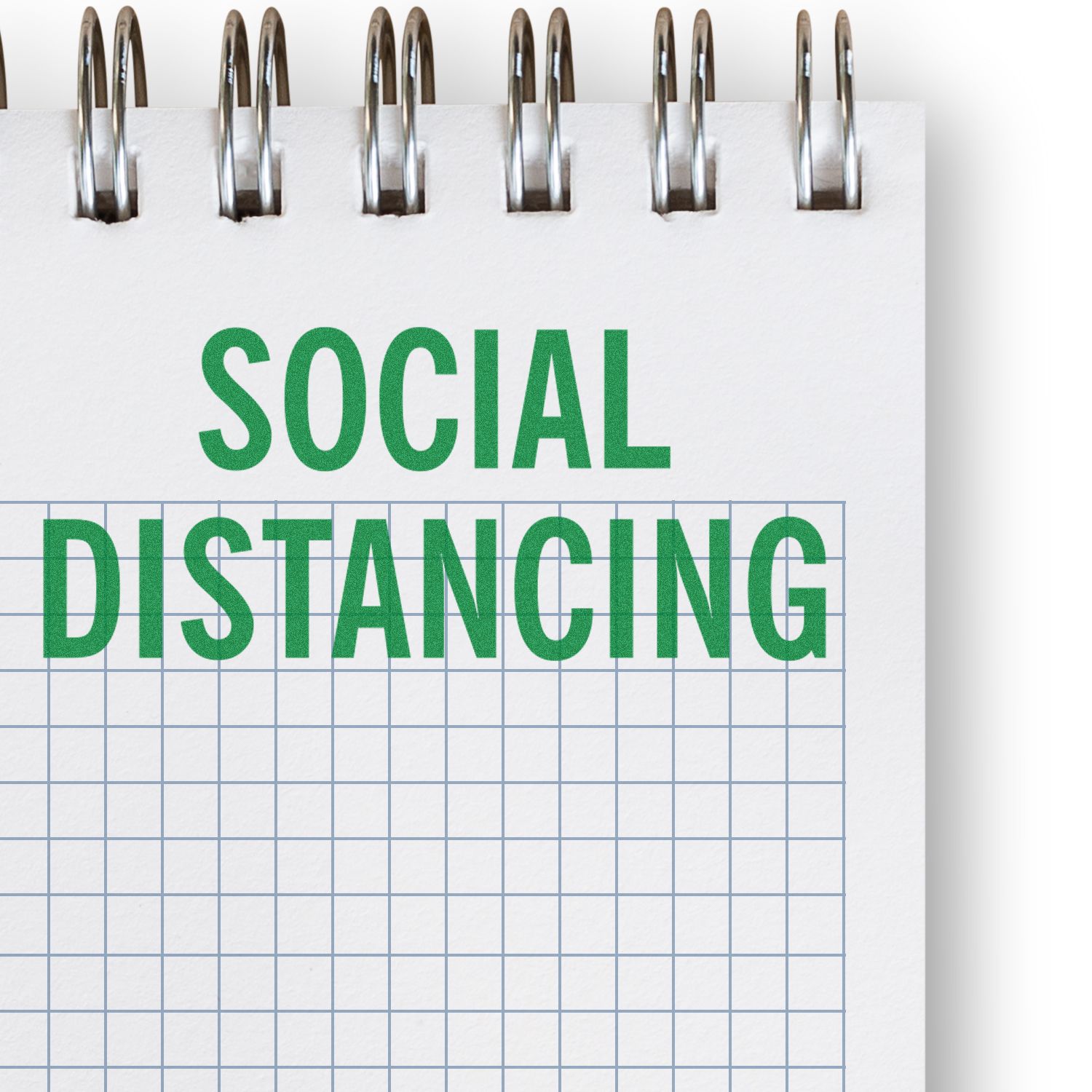 Large Social Distancing Rubber Stamp imprint on a grid notebook page, emphasizing the importance of maintaining social distance.