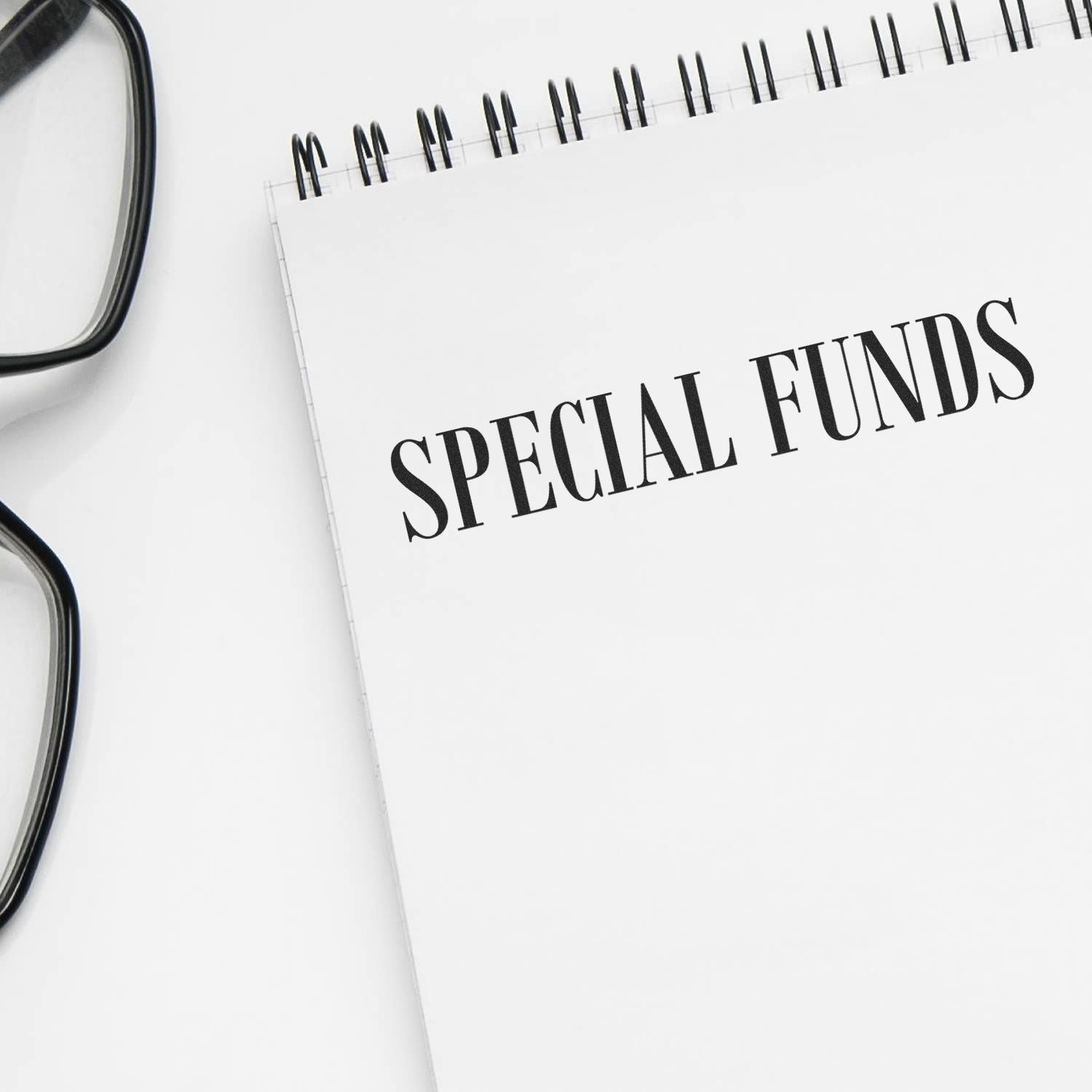 Large Self Inking Special Funds Stamp used on a white notepad with SPECIAL FUNDS text, next to black-framed glasses.