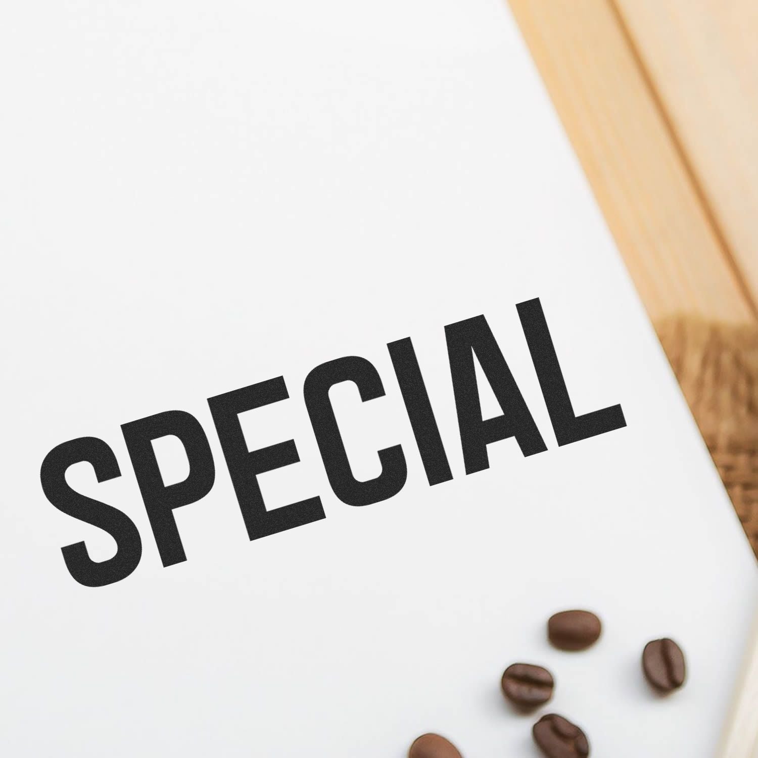 Large Self Inking Special Stamp imprinting the word 'SPECIAL' on white paper, with coffee beans scattered nearby on a wooden surface.