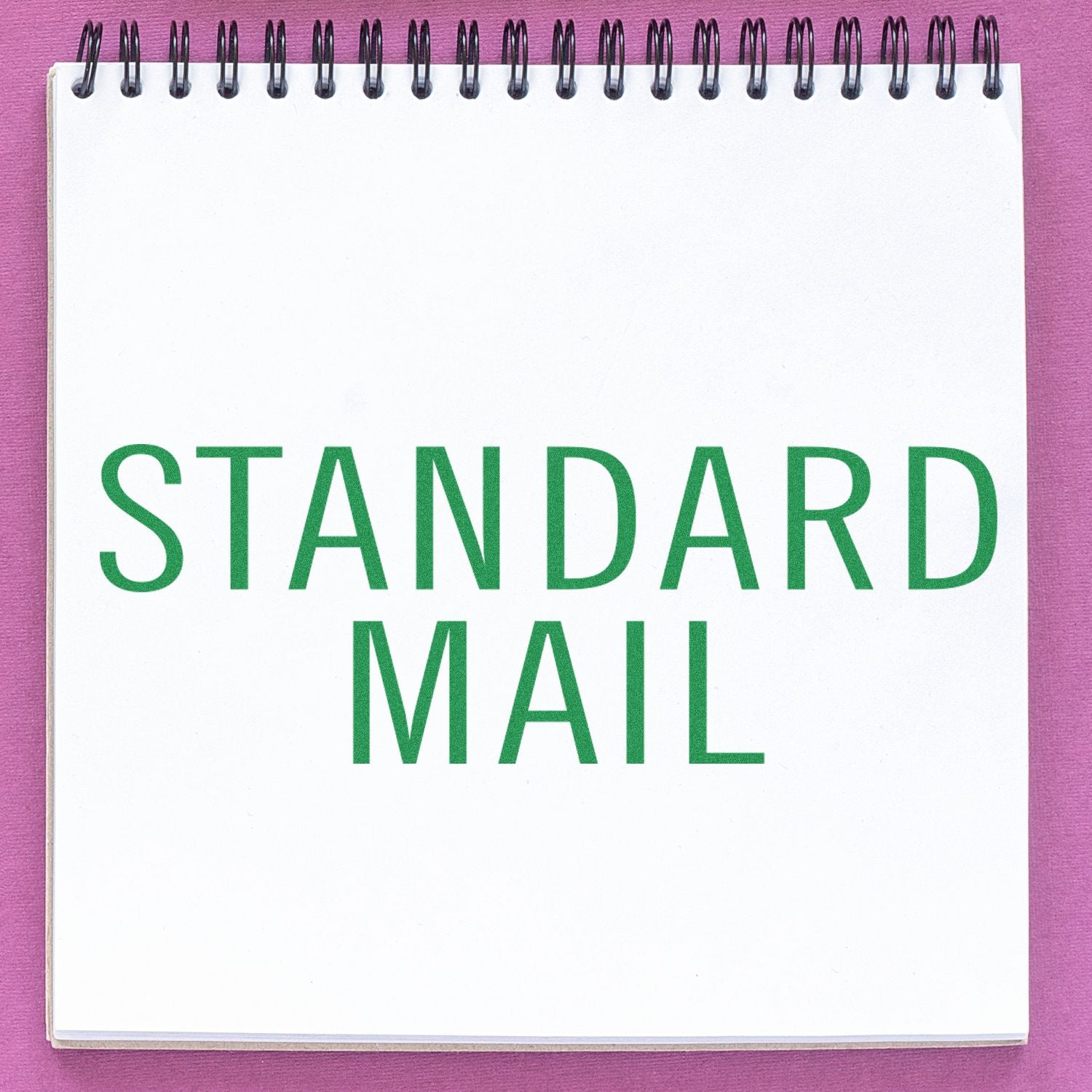 A notebook with STANDARD MAIL stamped in green using the Large Self Inking Standard Mail Stacked Stamp on a pink background.