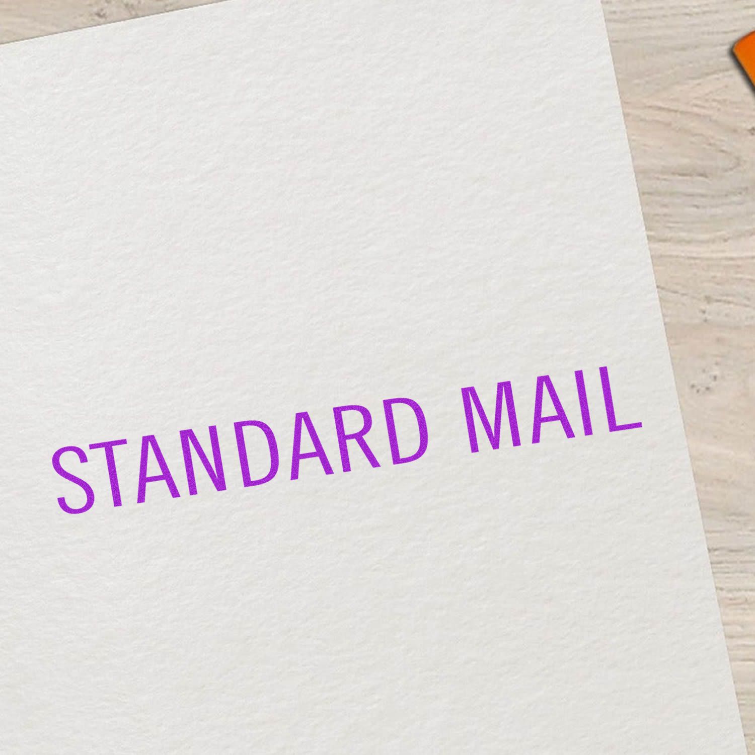 Standard Mail rubber stamp in purple ink on white paper, placed on a light wooden surface.