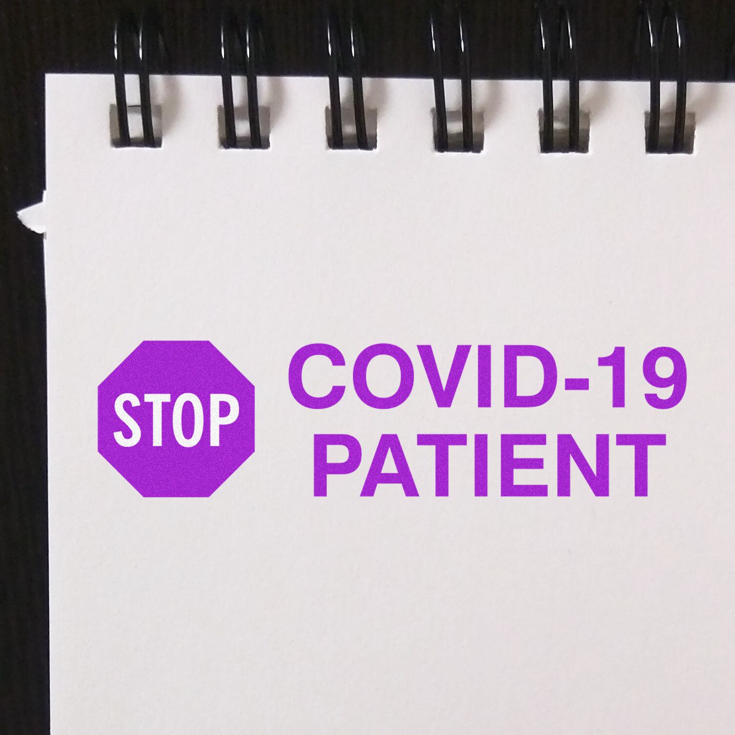 Large Pre-Inked Stop Covid-19 Patient Stamp in use, displaying a bold purple STOP COVID-19 PATIENT message on a white notepad.