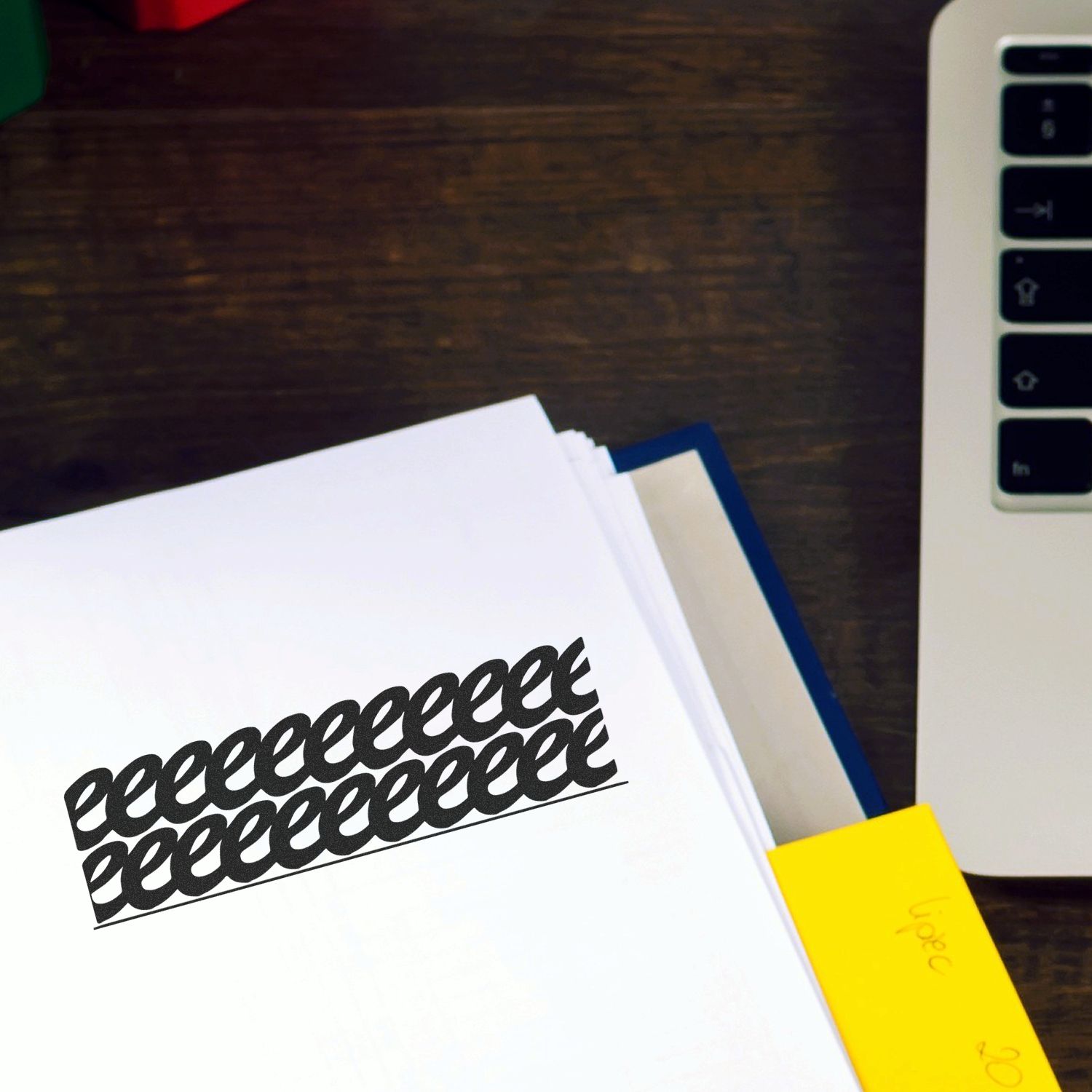 Strikeout Rubber Stamp used on a document, placed on a wooden desk next to a laptop and a yellow sticky note.