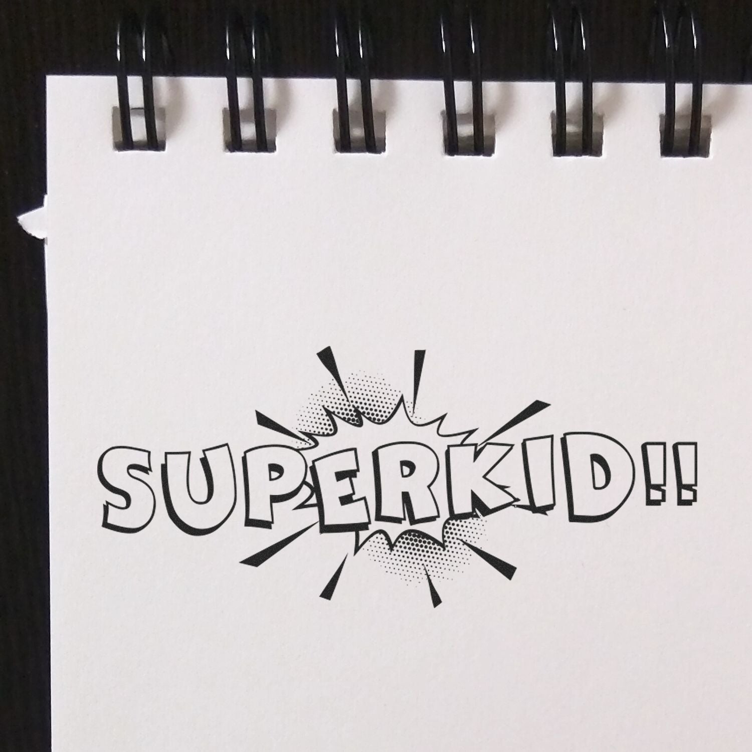 Notebook page stamped with 'SUPERKID!!' using the Large Self Inking Superkid Stamp, featuring bold comic-style text and starburst design.