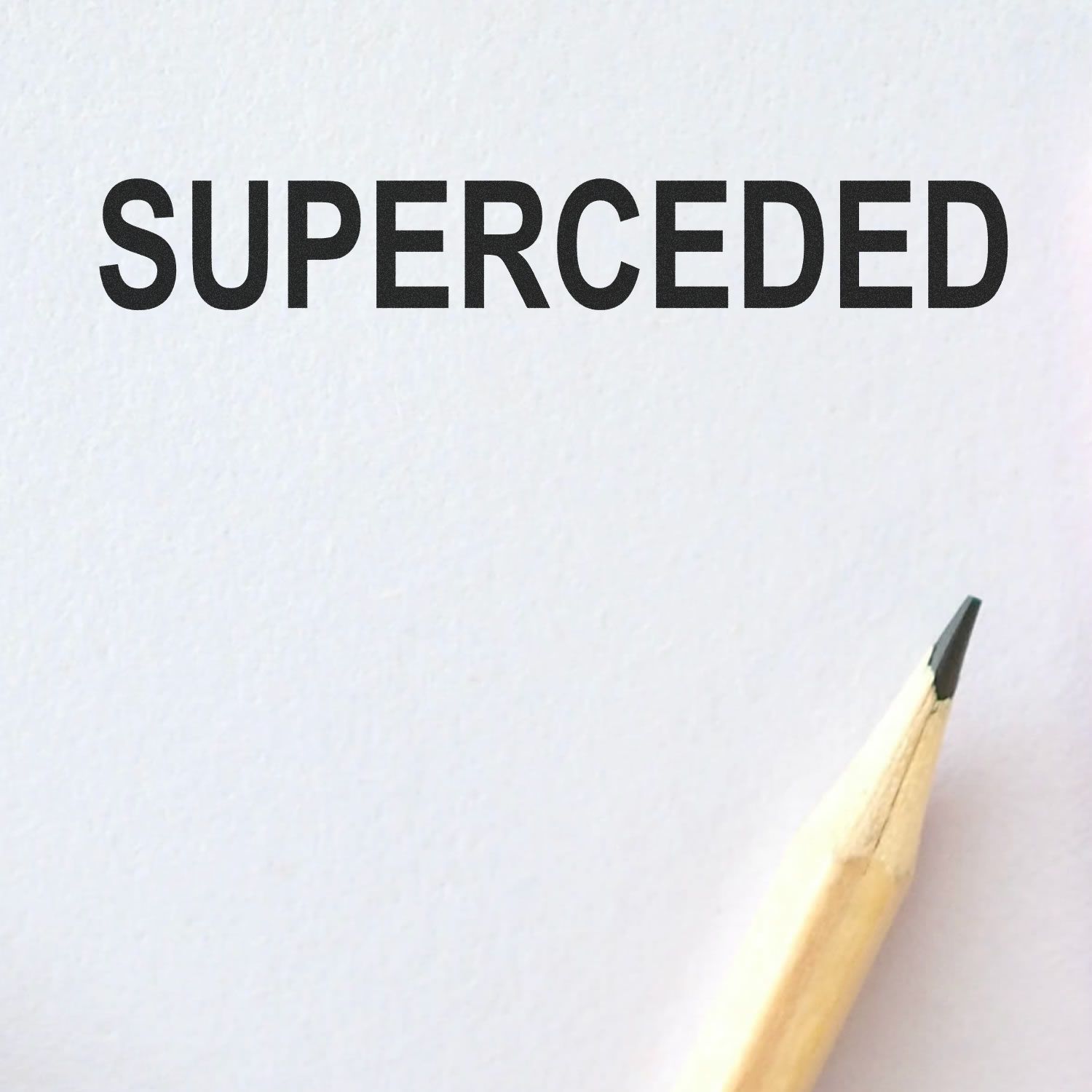 Self Inking Superceded Stamp marking 'SUPERCEDED' on white paper with a pencil tip visible in the bottom right corner.