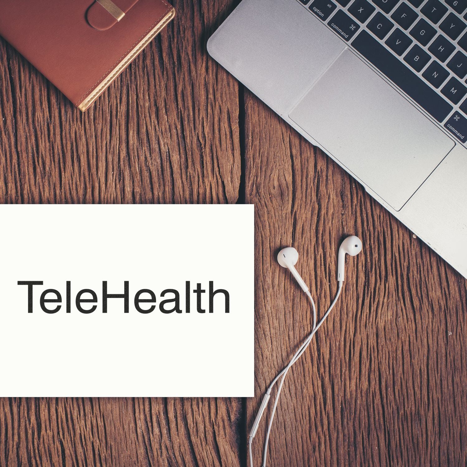 Large Self Inking Telehealth Stamp on a wooden desk next to a laptop, earphones, and a brown notebook.