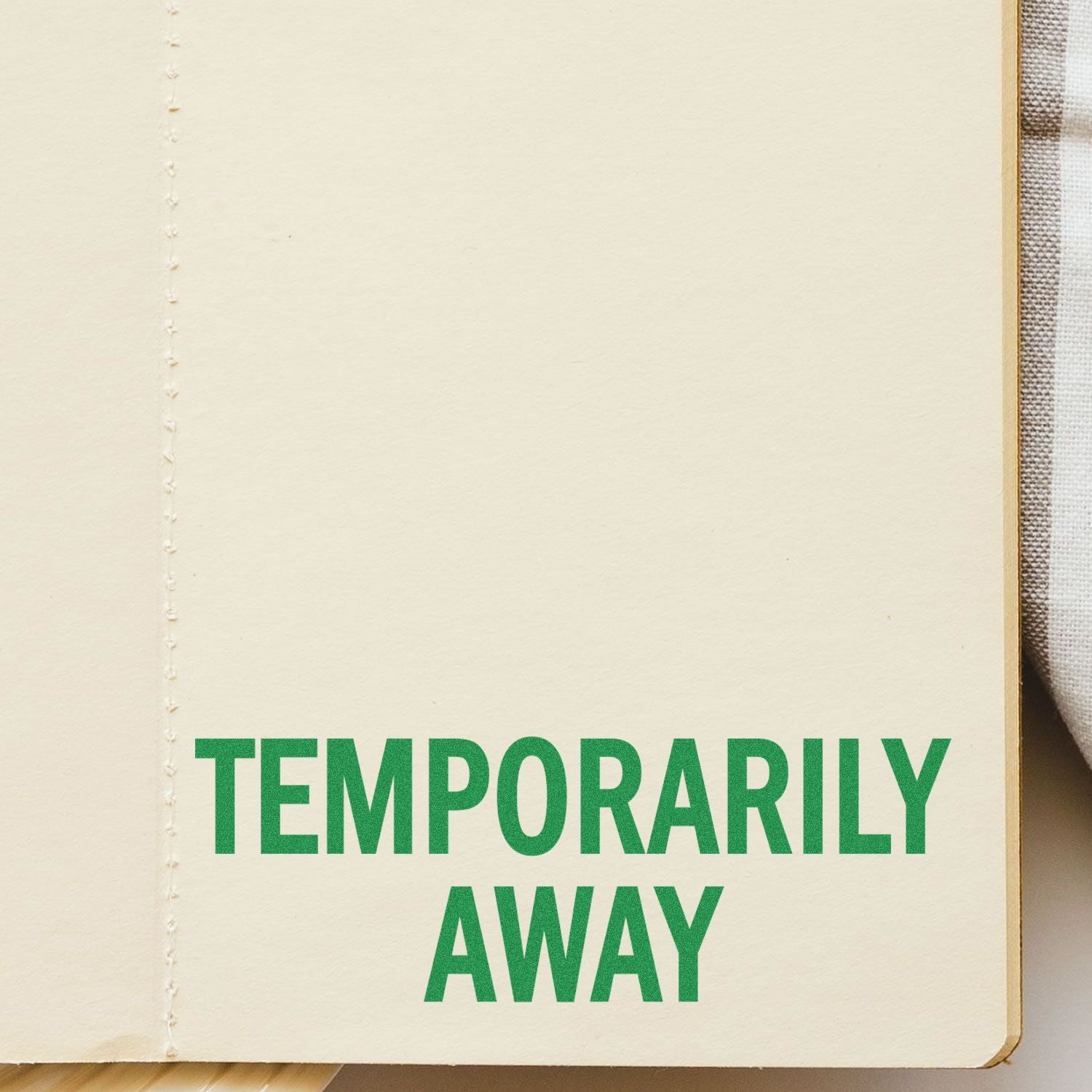 Slim Pre-Inked Temporarily Away Stamp in green ink on a beige notebook page, indicating a temporary absence.