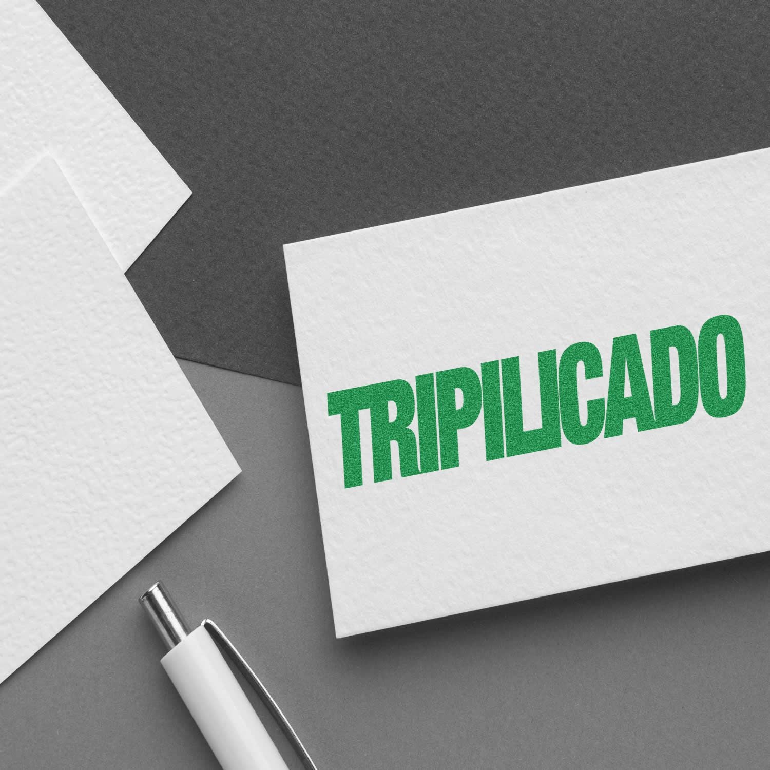 Large Tripilicado Rubber Stamp imprint in green on white paper, with a pen and additional sheets in the background.