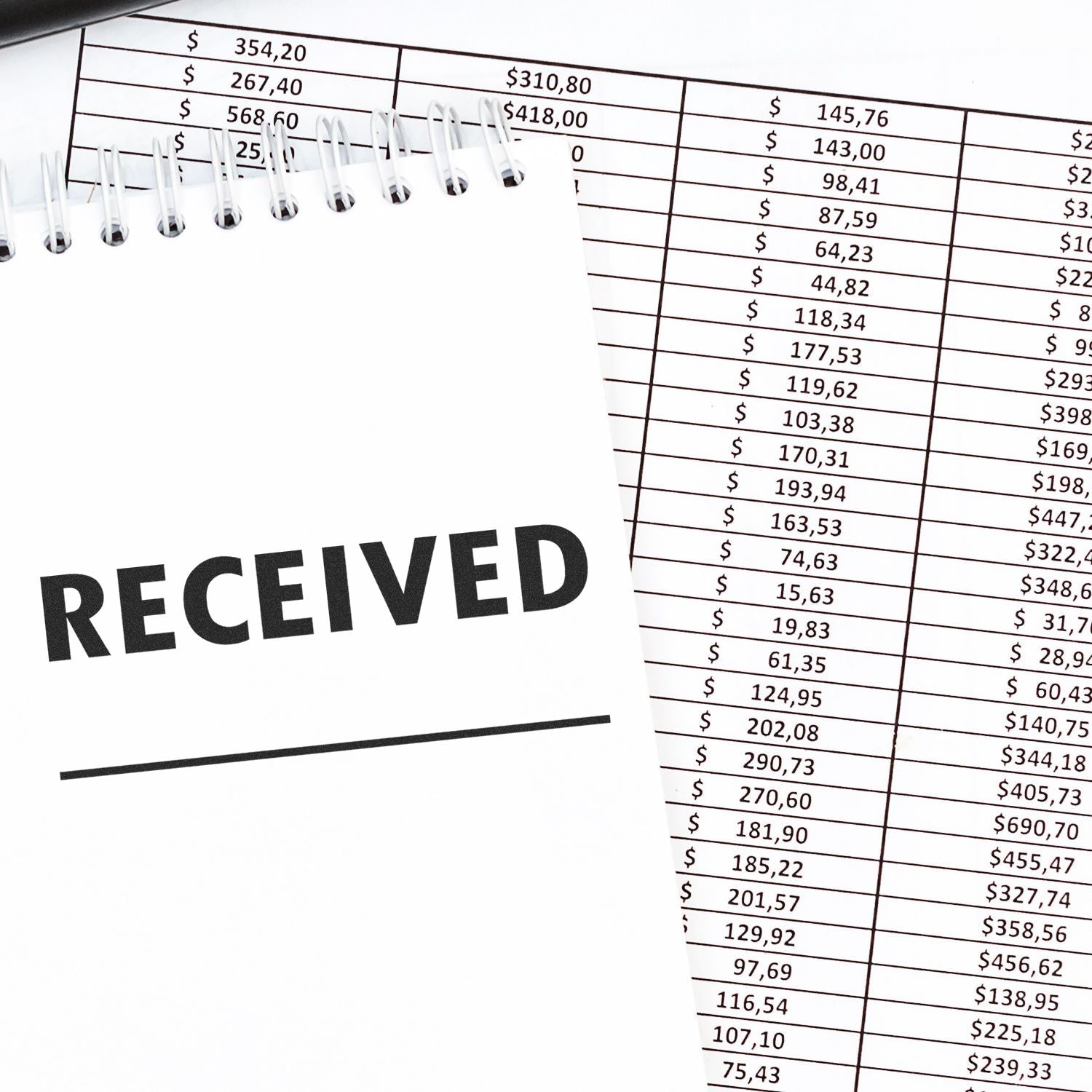 Large Two Line Received Rubber Stamp on a notepad next to financial documents with numbers and dollar amounts.