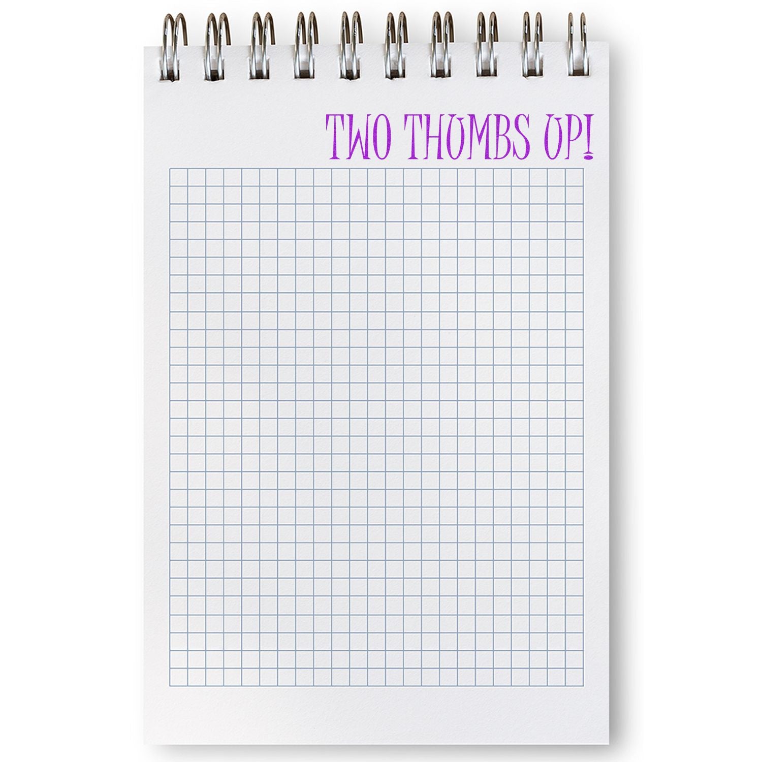 A notepad with a grid pattern and the words TWO THUMBS UP! stamped at the top in purple using a large two thumbs up rubber stamp.