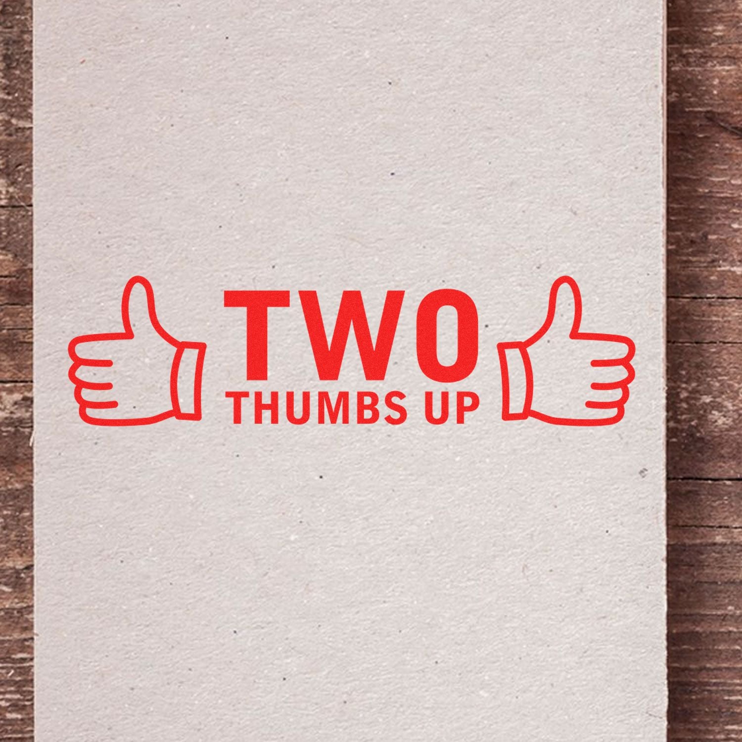 Two Thumbs Up with Thumb Icon Rubber Stamp in red ink on a beige paper, featuring two thumbs up icons on either side.