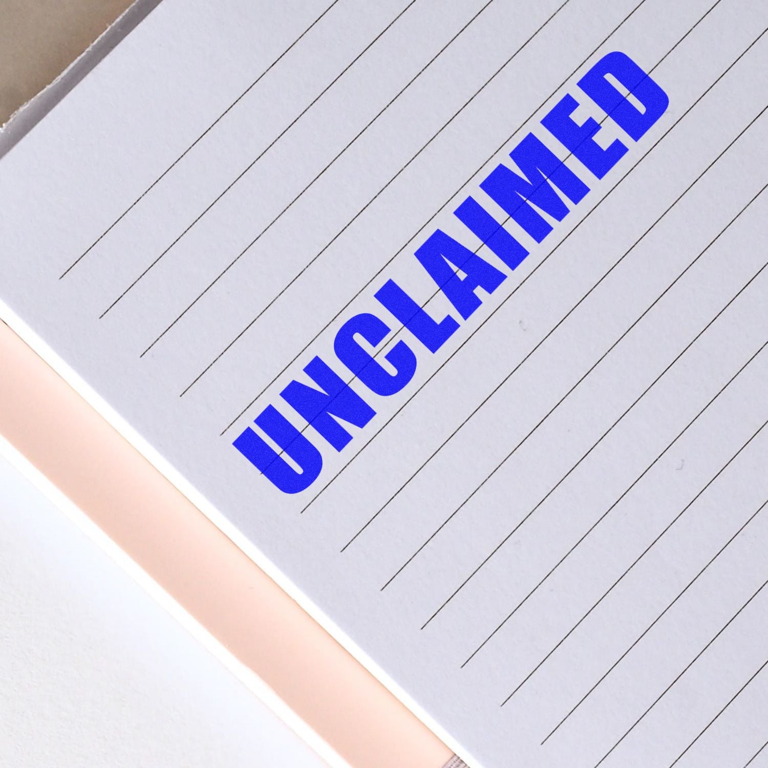 A lined paper with the word "UNCLAIMED" stamped in bold blue letters using the Unclaimed Rubber Stamp.