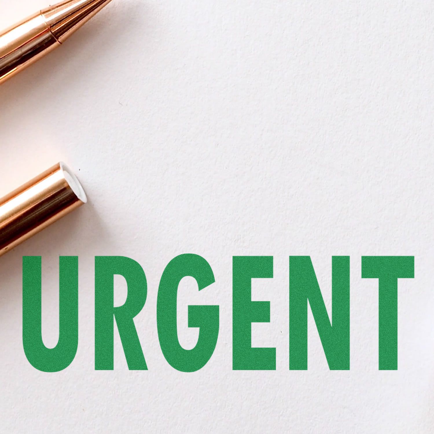 Large Urgent Rubber Stamp in green ink on white paper, with two gold pens placed nearby.