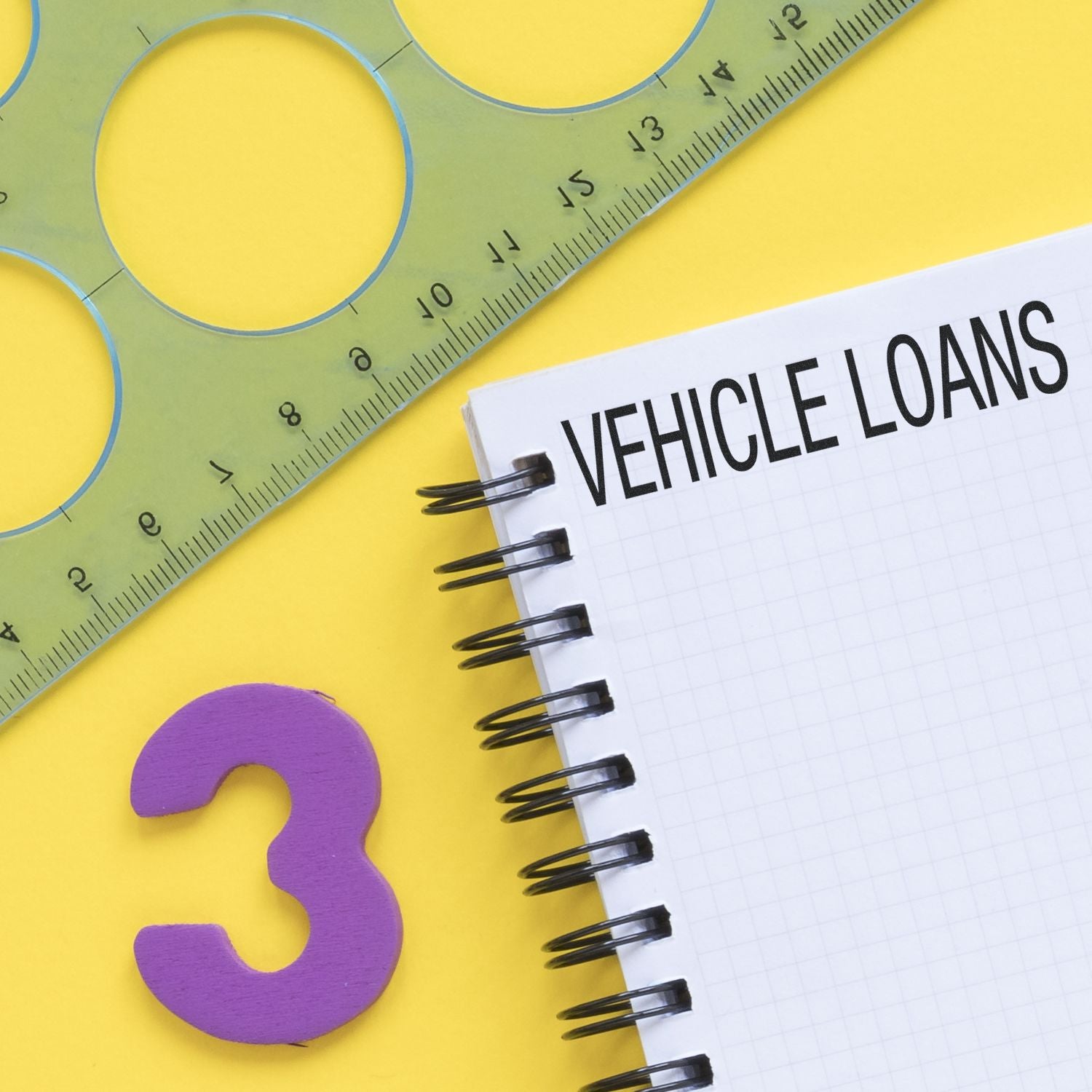 Large Pre-Inked Vehicle Loans Stamp used on a notebook with a green ruler and purple number three on a yellow background.