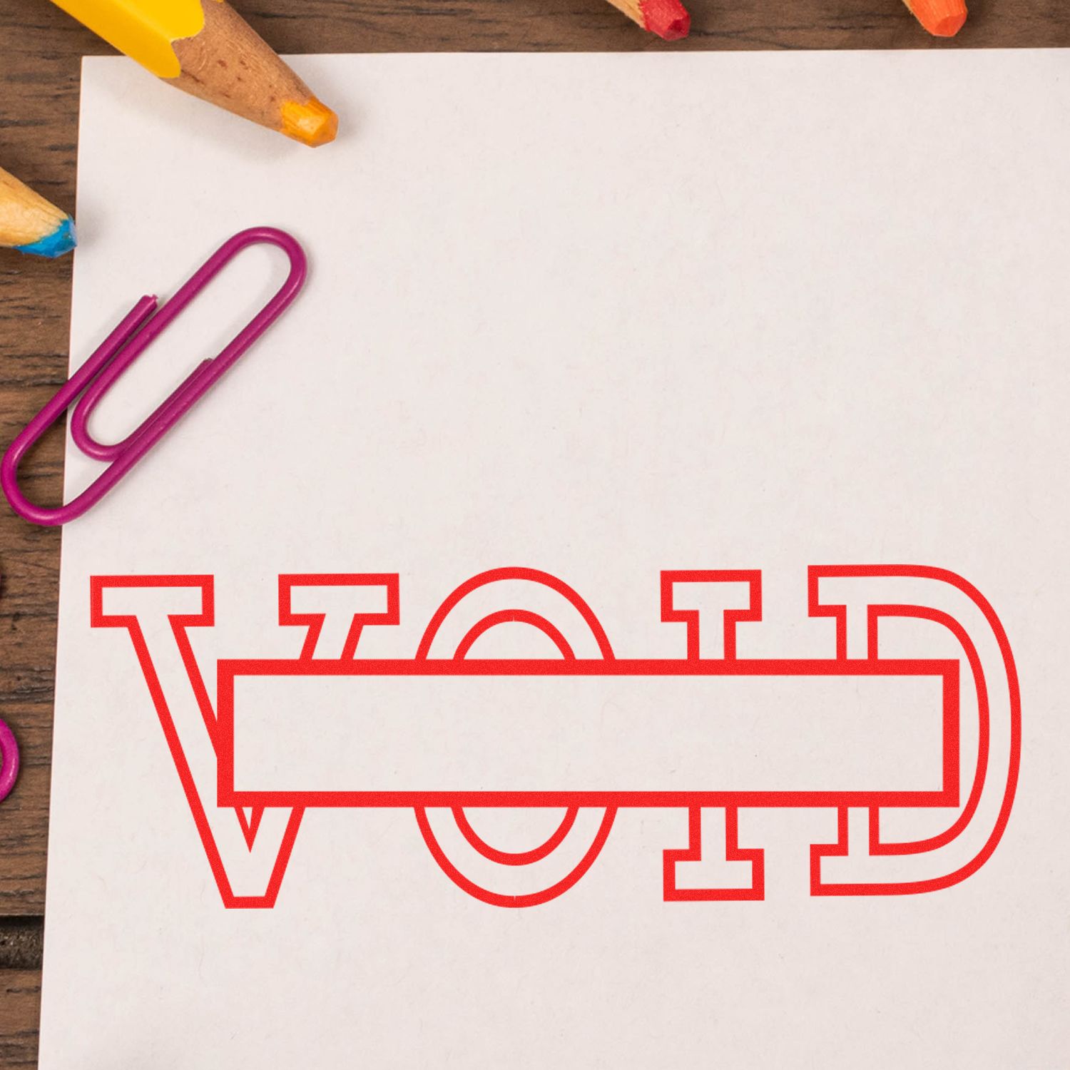 Large Void with Box Rubber Stamp in red ink on white paper, surrounded by colorful pencils and a purple paperclip.