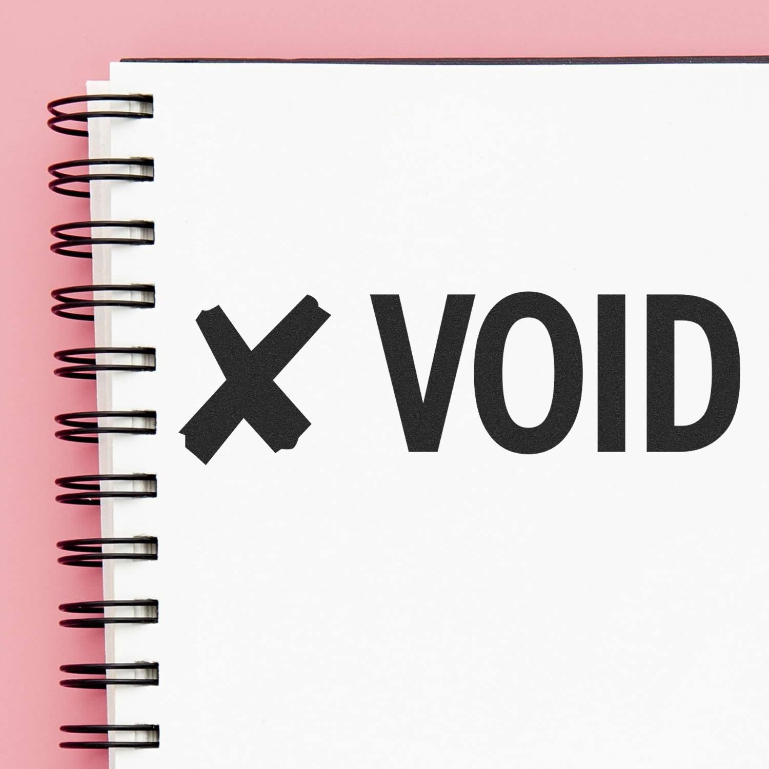 Large Void with X Rubber Stamp impression on a white spiral notebook page against a pink background.