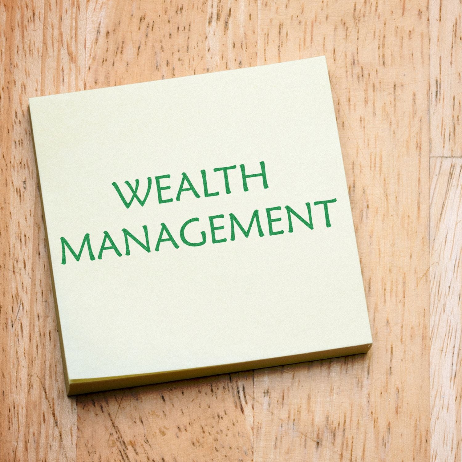 Large Wealth Management rubber stamp on a wooden surface, with Wealth Management text prominently displayed on a yellow sticky note.