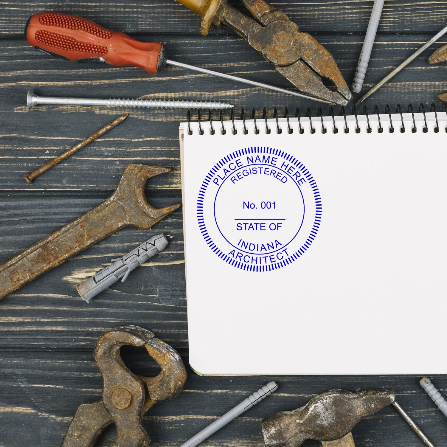 Digital Indiana Architect Stamp, Electronic Seal for Indiana Architect, displayed on a notepad surrounded by various tools on a wooden surface.