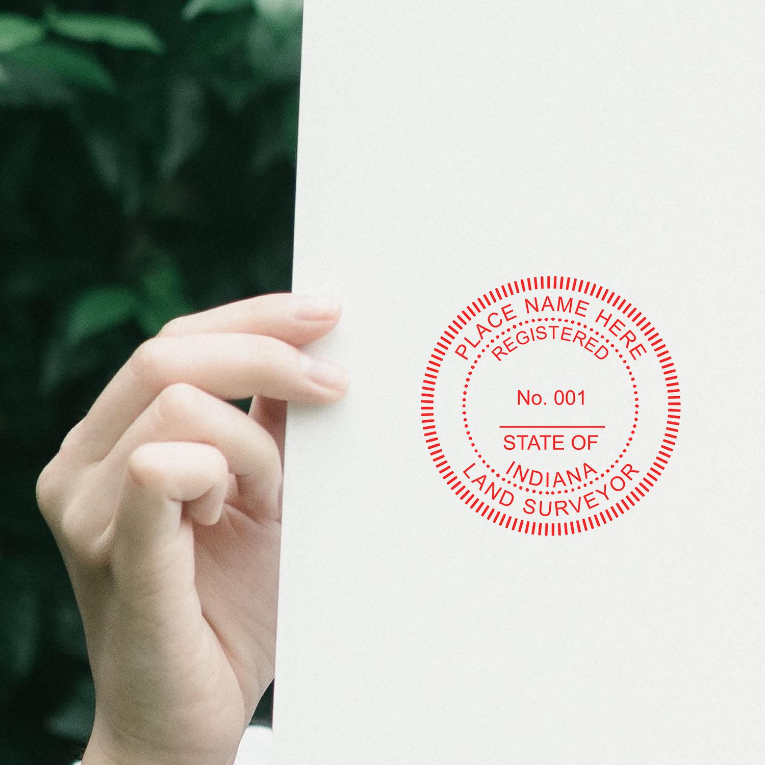 Person holding a paper with a red Digital Indiana Land Surveyor Stamp, Electronic Seal for Indiana Land Surveyor, against a green background.