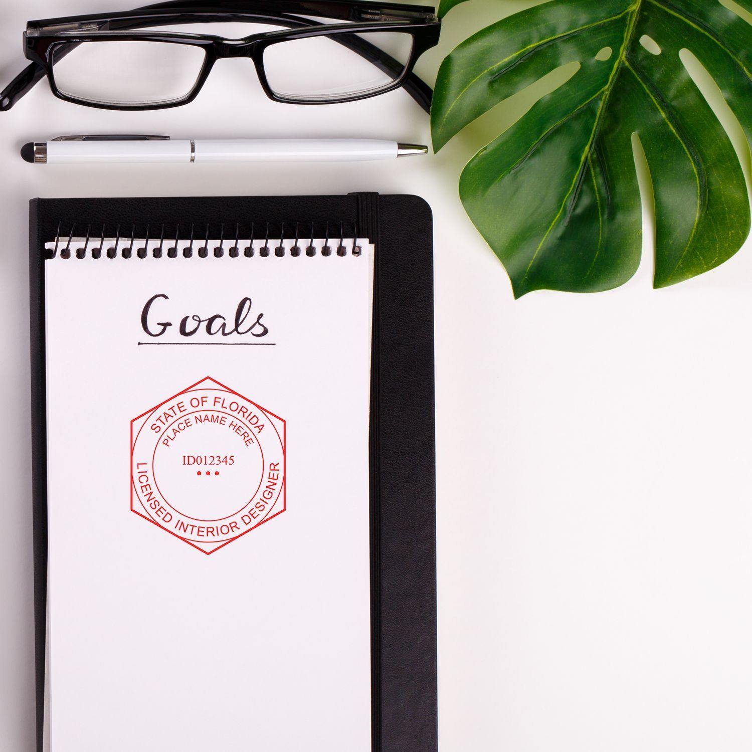 A notebook with Goals written on it, stamped with the Interior Designer eSeal Electronic Image Stamp of Seal, next to glasses and a pen.