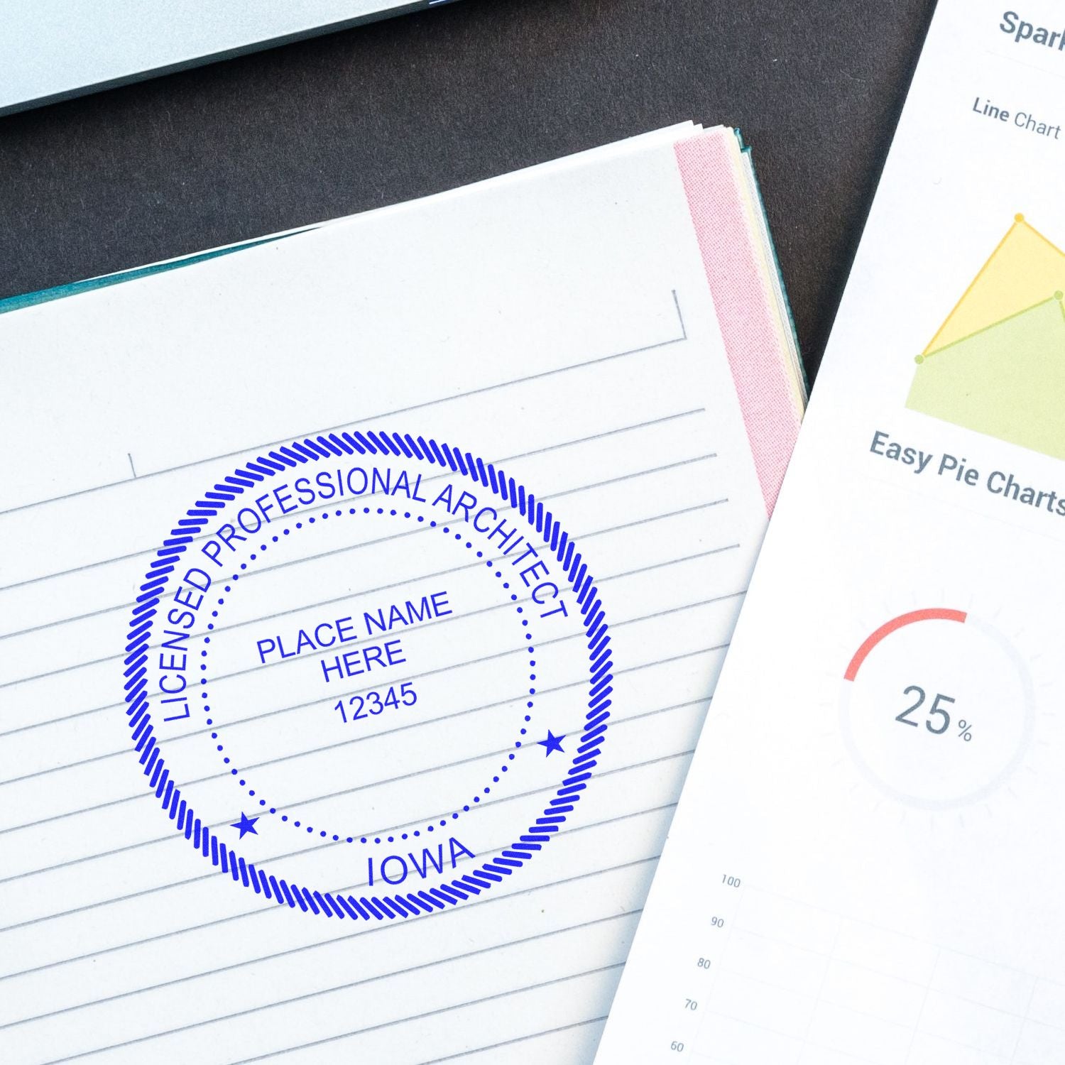 Self Inking Iowa Architect Stamp imprint on a notebook page, next to a chart document on a desk.