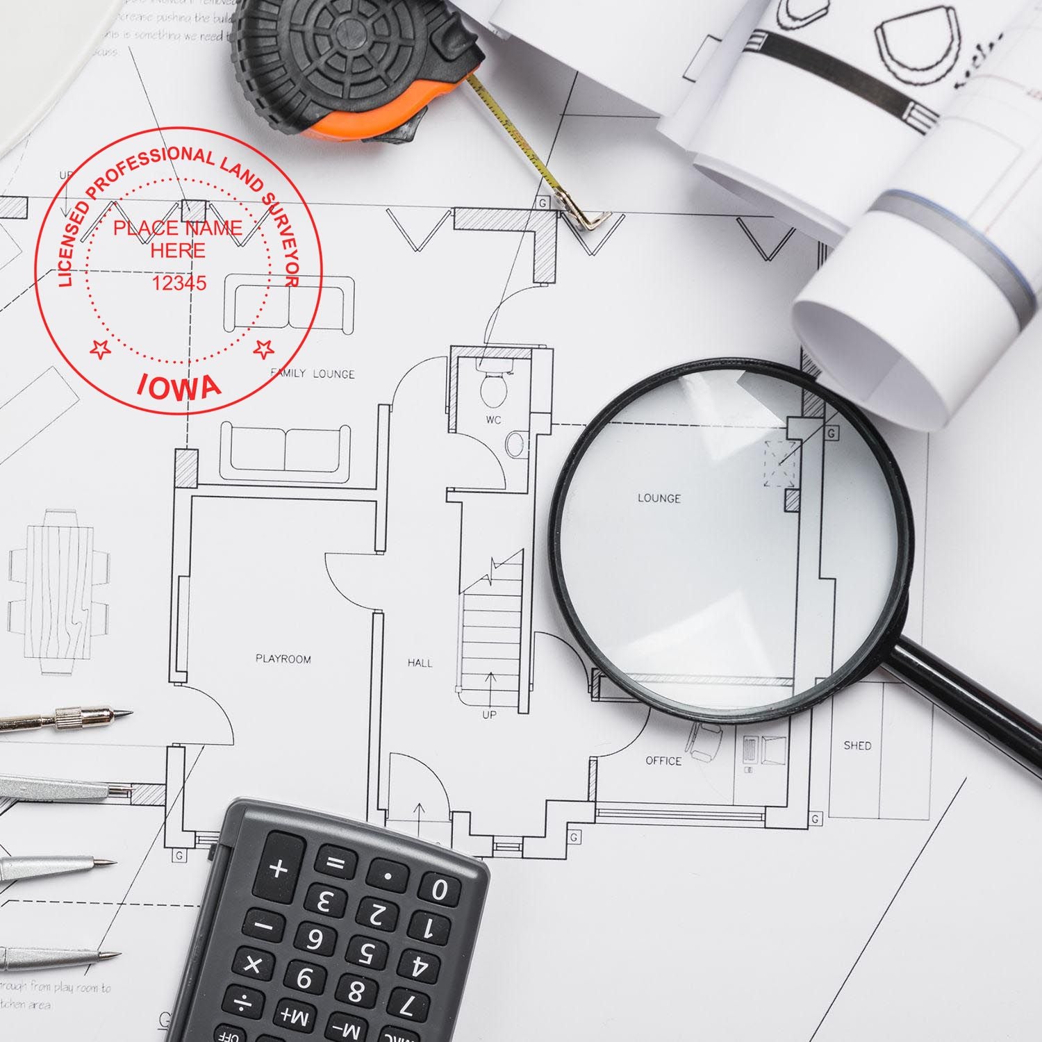 Premium MaxLight Pre-Inked Iowa Surveyors Stamp in use on architectural plans, surrounded by a magnifying glass, calculator, and measuring tape.