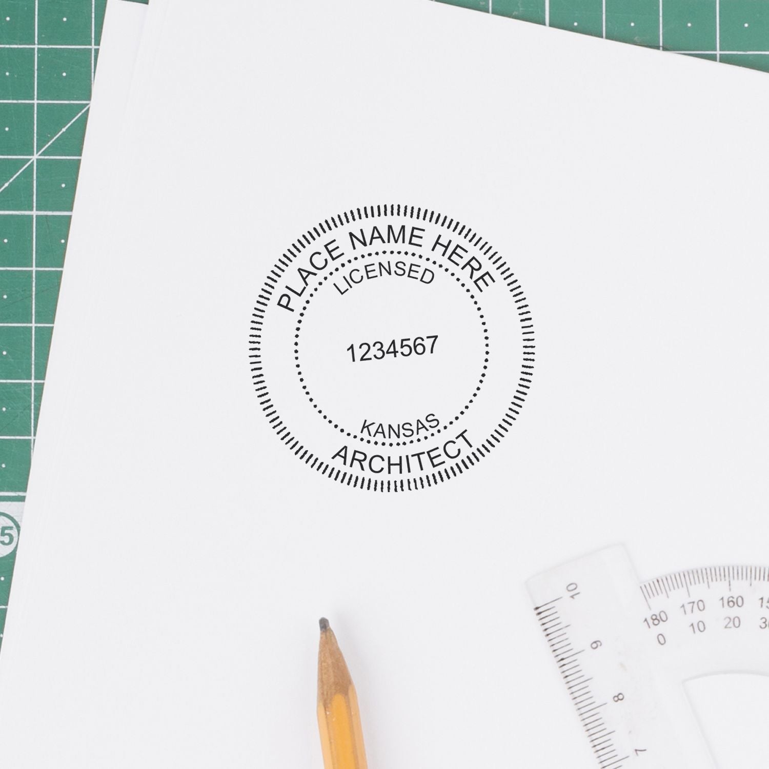 Self Inking Kansas Architect Stamp in use on white paper, next to a pencil and ruler on a green cutting mat.