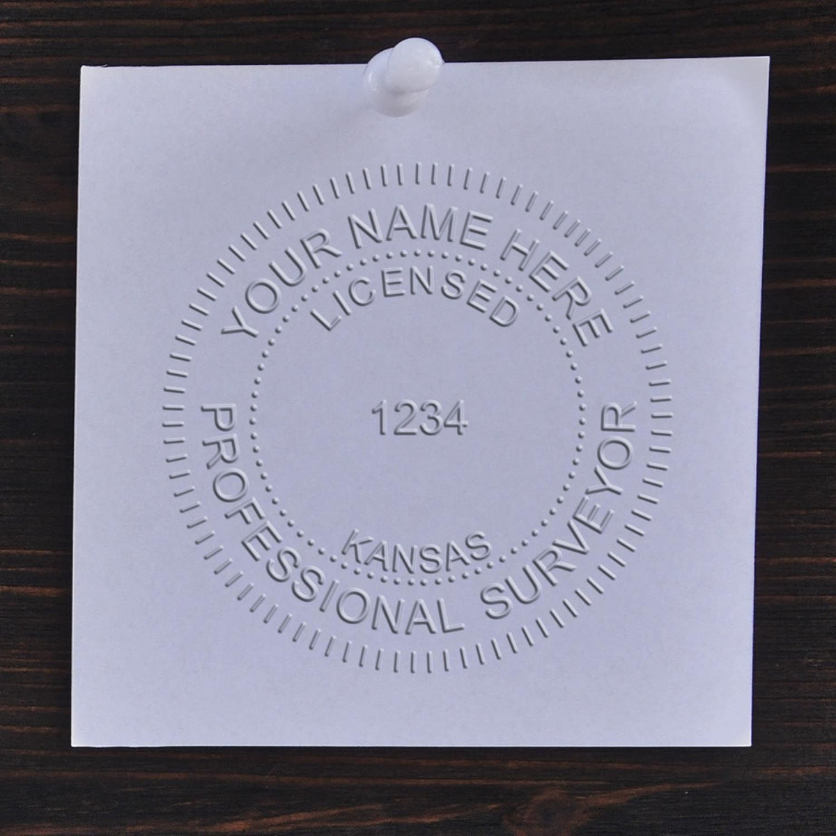 A lifestyle photo showing a stamped image of the Kansas Desk Surveyor Seal Embosser on a piece of paper