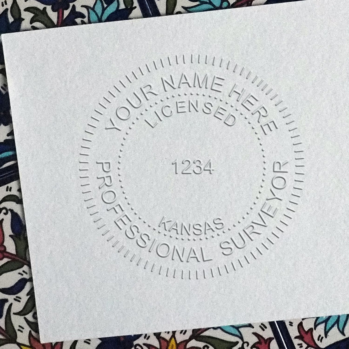 An in use photo of the Hybrid Kansas Land Surveyor Seal showing a sample imprint on a cardstock