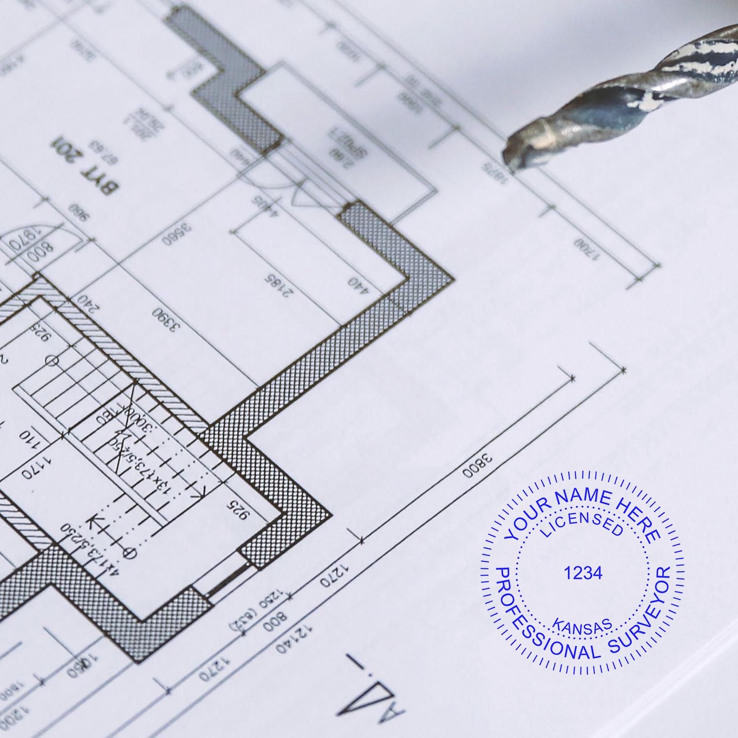 Premium MaxLight Pre-Inked Kansas Surveyors Stamp in blue ink on a detailed architectural blueprint with a pen tip nearby.