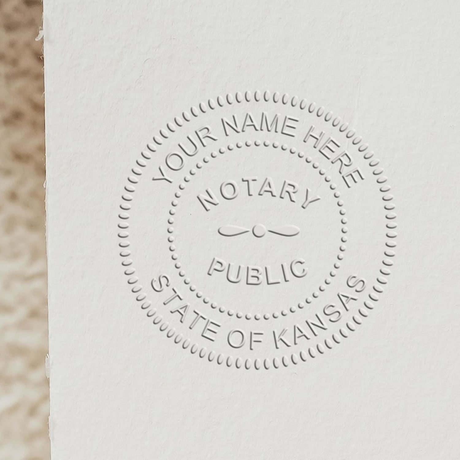 A lifestyle photo showing a stamped image of the Kansas Handheld Notary Seal Embosser on a piece of paper