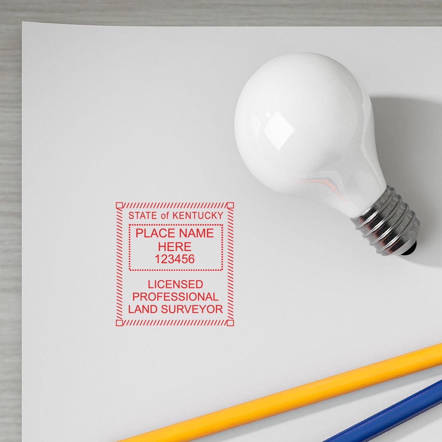 Kentucky Land Surveyor Seal Stamp on white paper, next to a light bulb and pencils. The stamp reads "Licensed Professional Land Surveyor."