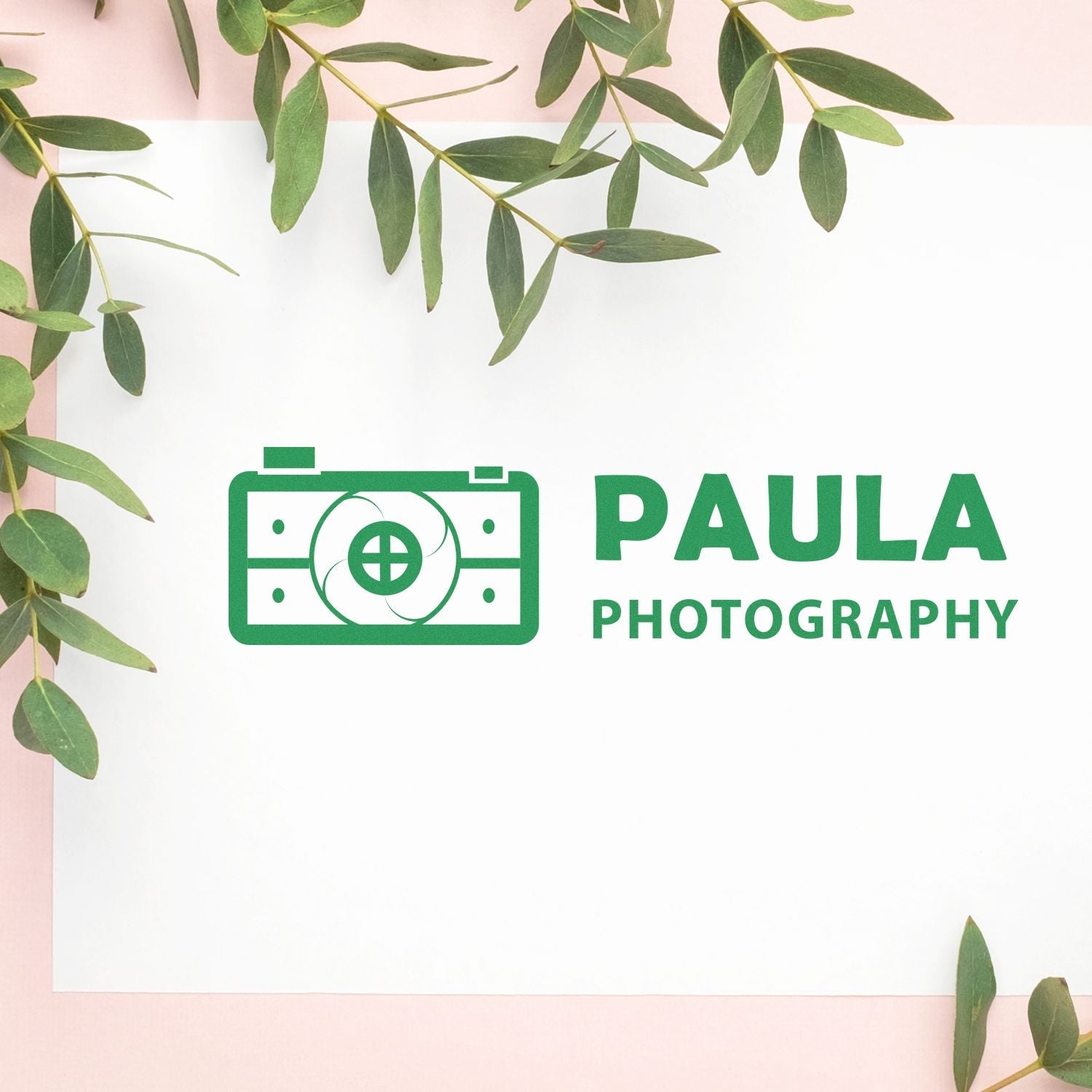 Custom Rubber Stamp Size 1-1/2 x 5 in use, stamping PAULA PHOTOGRAPHY logo in green on white paper with green leaves around.