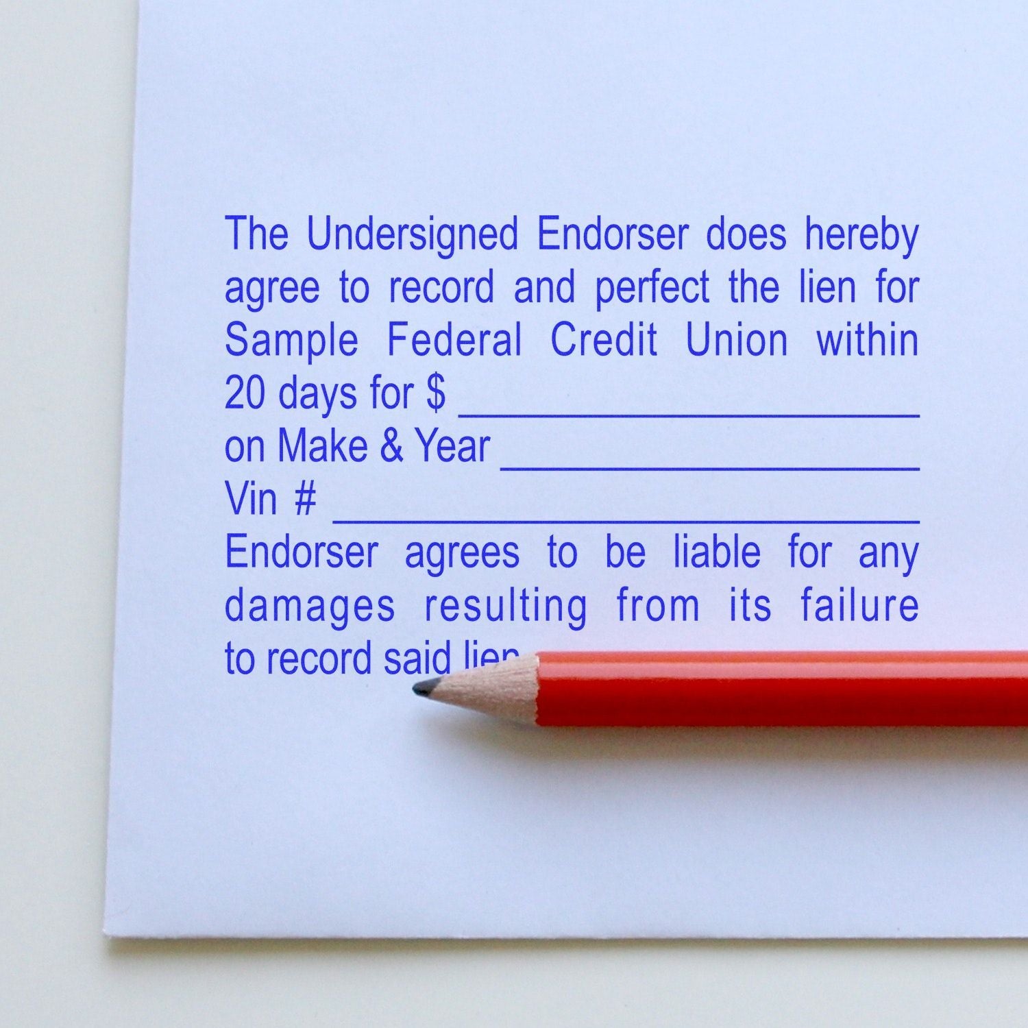 A red pencil rests on a document stamped with blue ink using the 10 Line Custom Rubber Stamp with Wood Handle, showing detailed text.